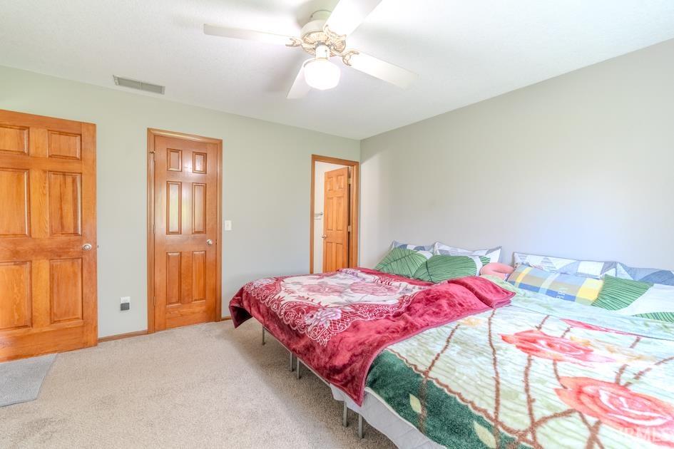 Bedroom with light carpet and a ceiling fan