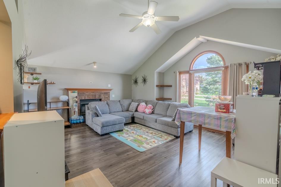 Living room featuring a fireplace, a ceiling fan, and dark wood-style floors