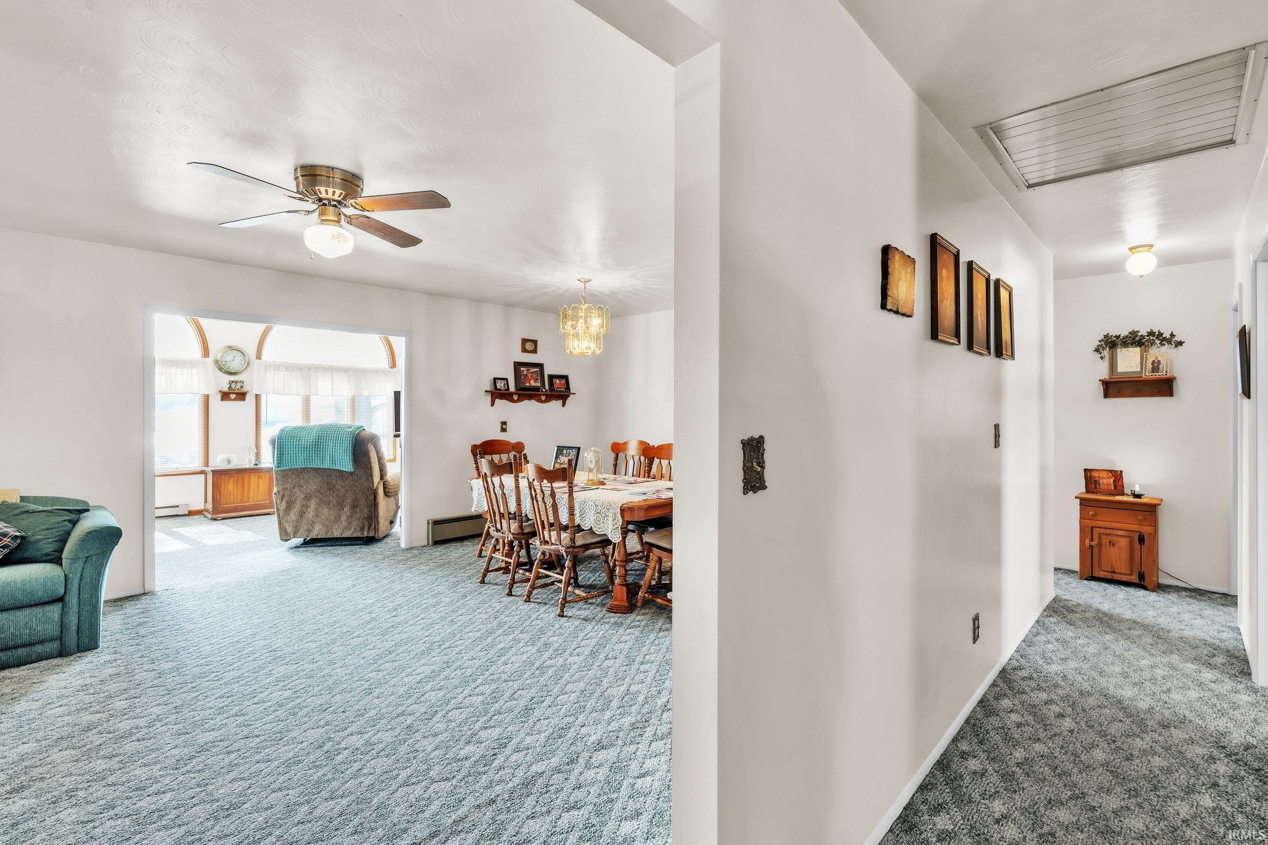 Corridor featuring carpet floors, a chandelier, and a baseboard heating unit