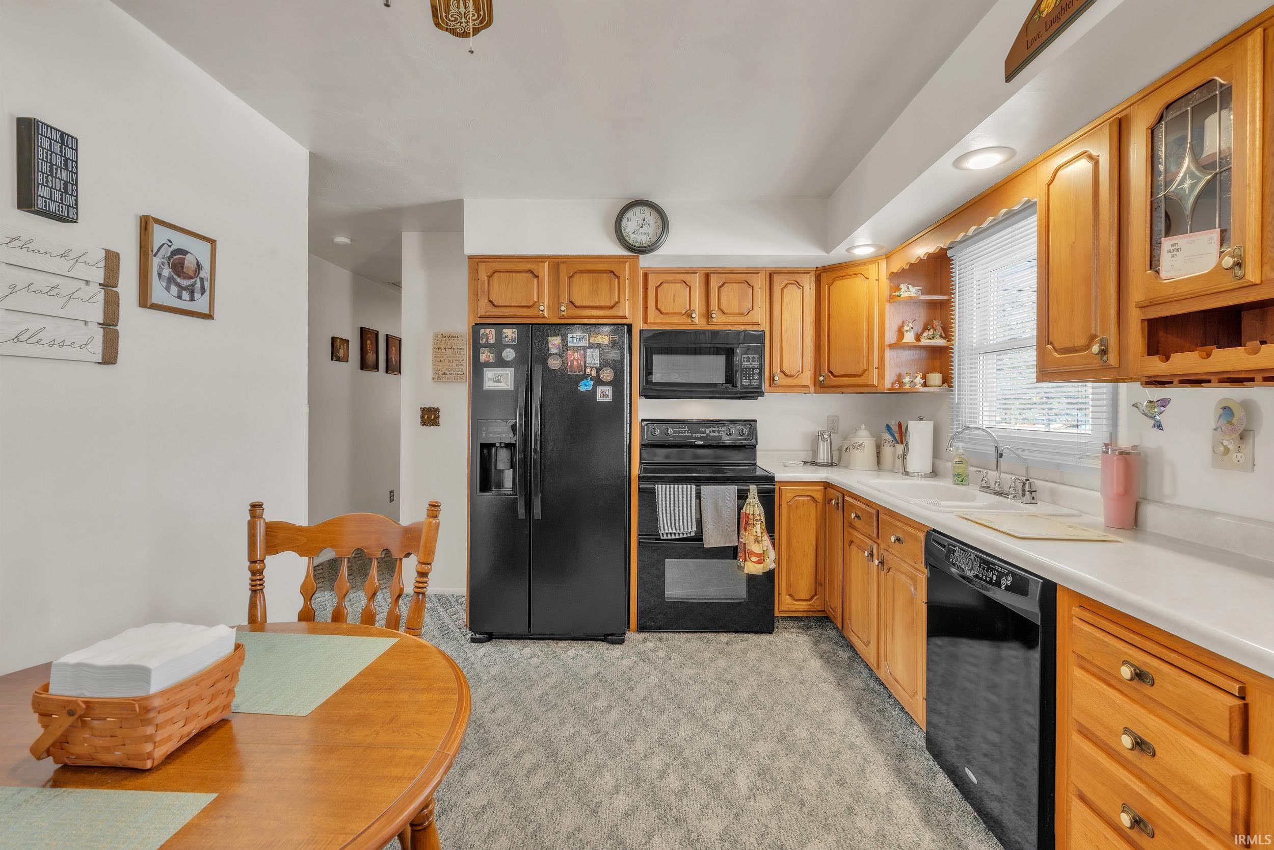 Kitchen with black appliances, open shelves, light countertops, recessed lighting, and light carpet