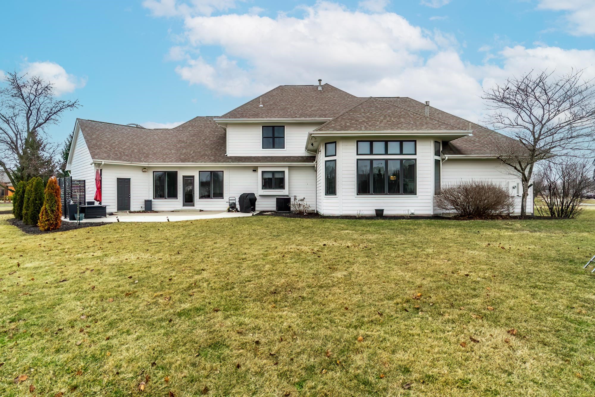 Back of property with a patio area, a shingled roof, and a lawn