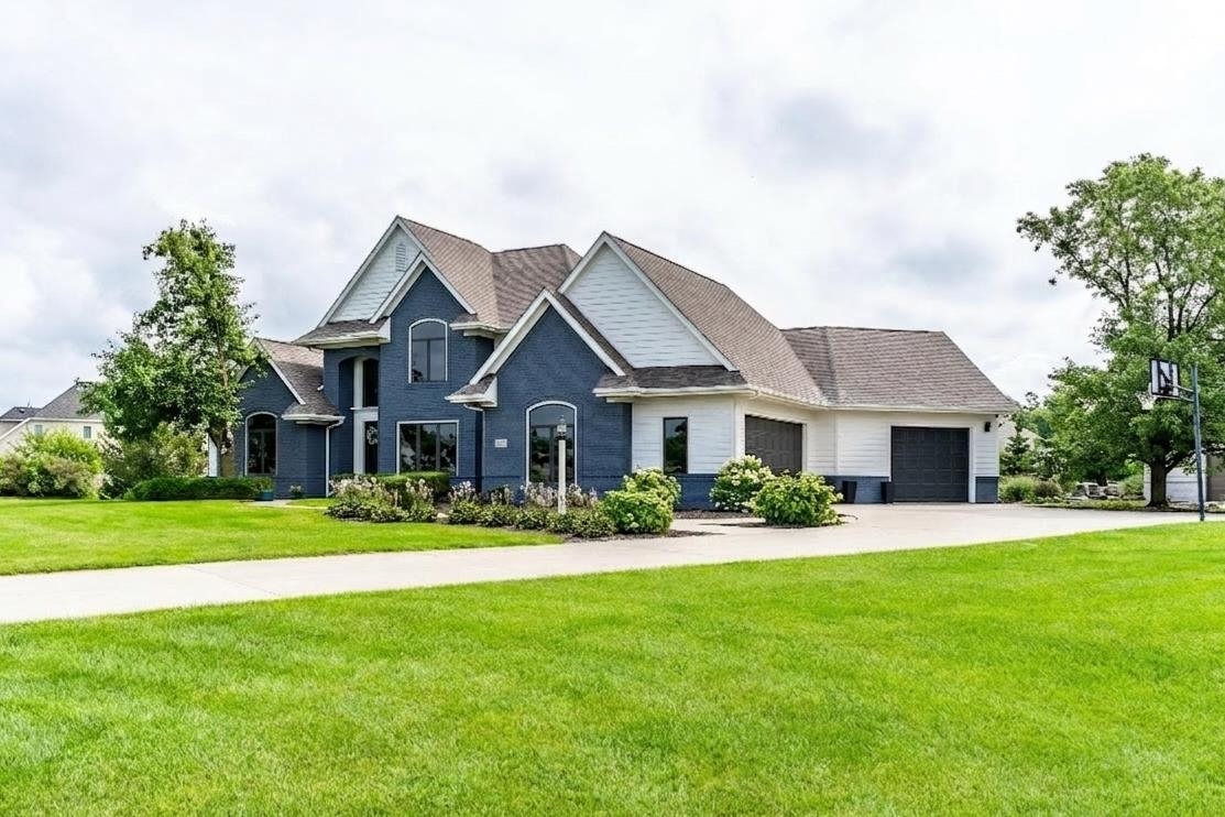 View of front of house with a front lawn, driveway, and an attached garage