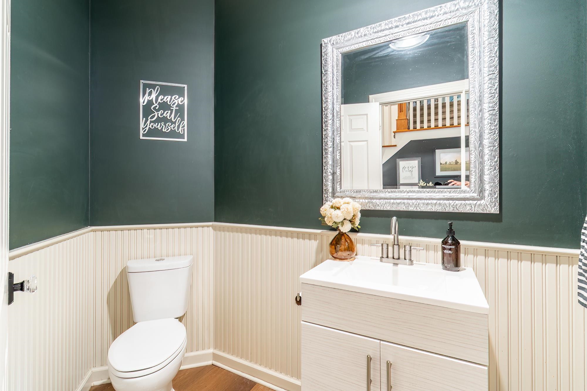 Half bath with vanity, wainscoting, and wood finished floors