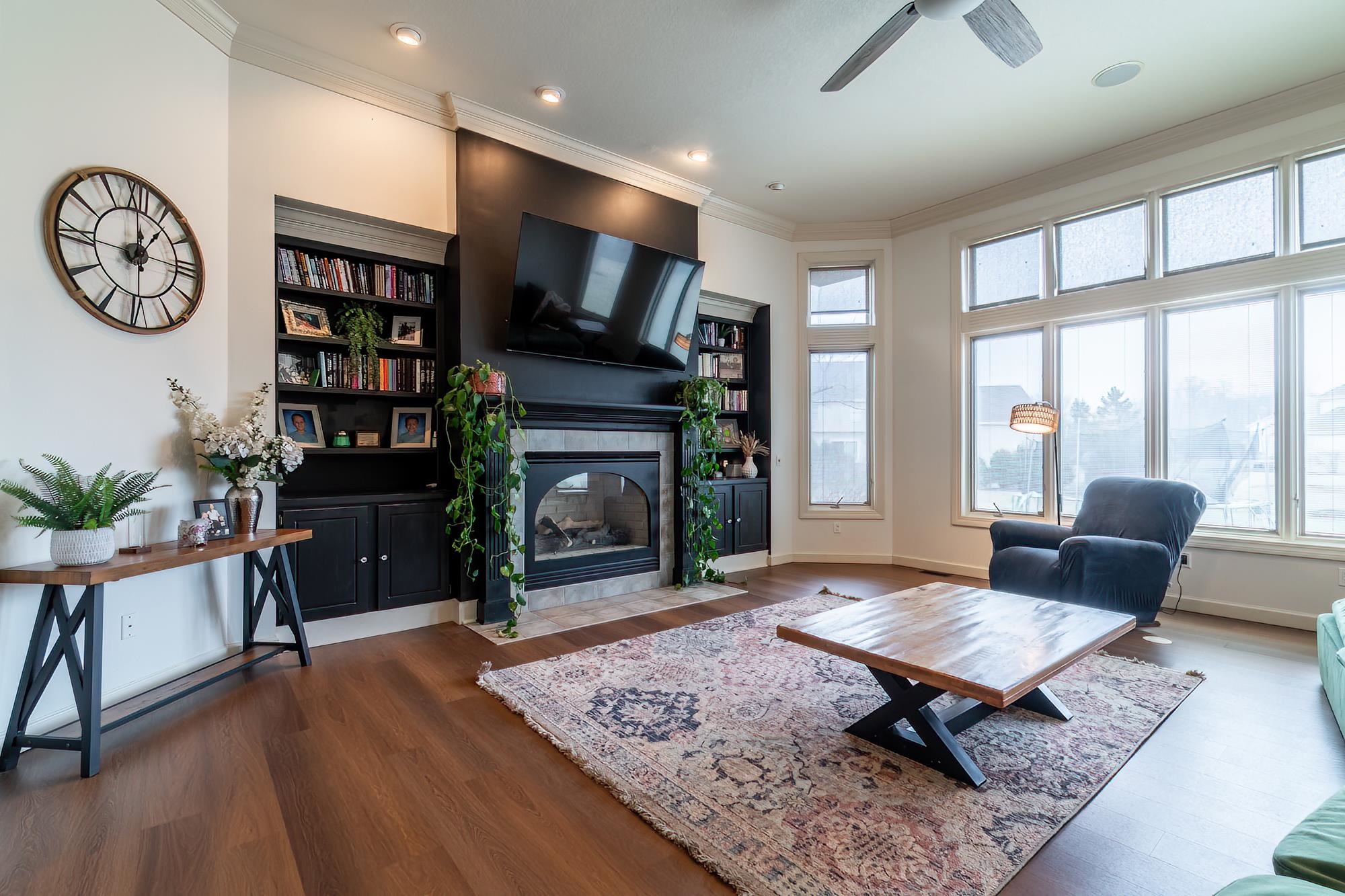 Living room featuring built in features, a ceiling fan, dark wood-style flooring, a tiled fireplace, and recessed lighting