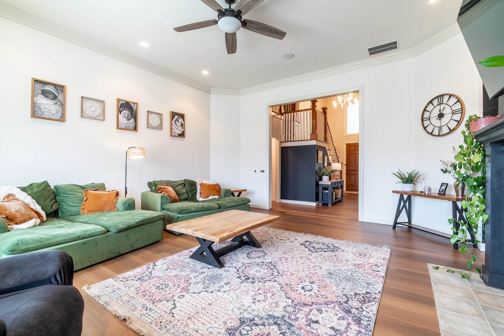 Living area with ornamental molding, a ceiling fan, wood finished floors, and a chandelier