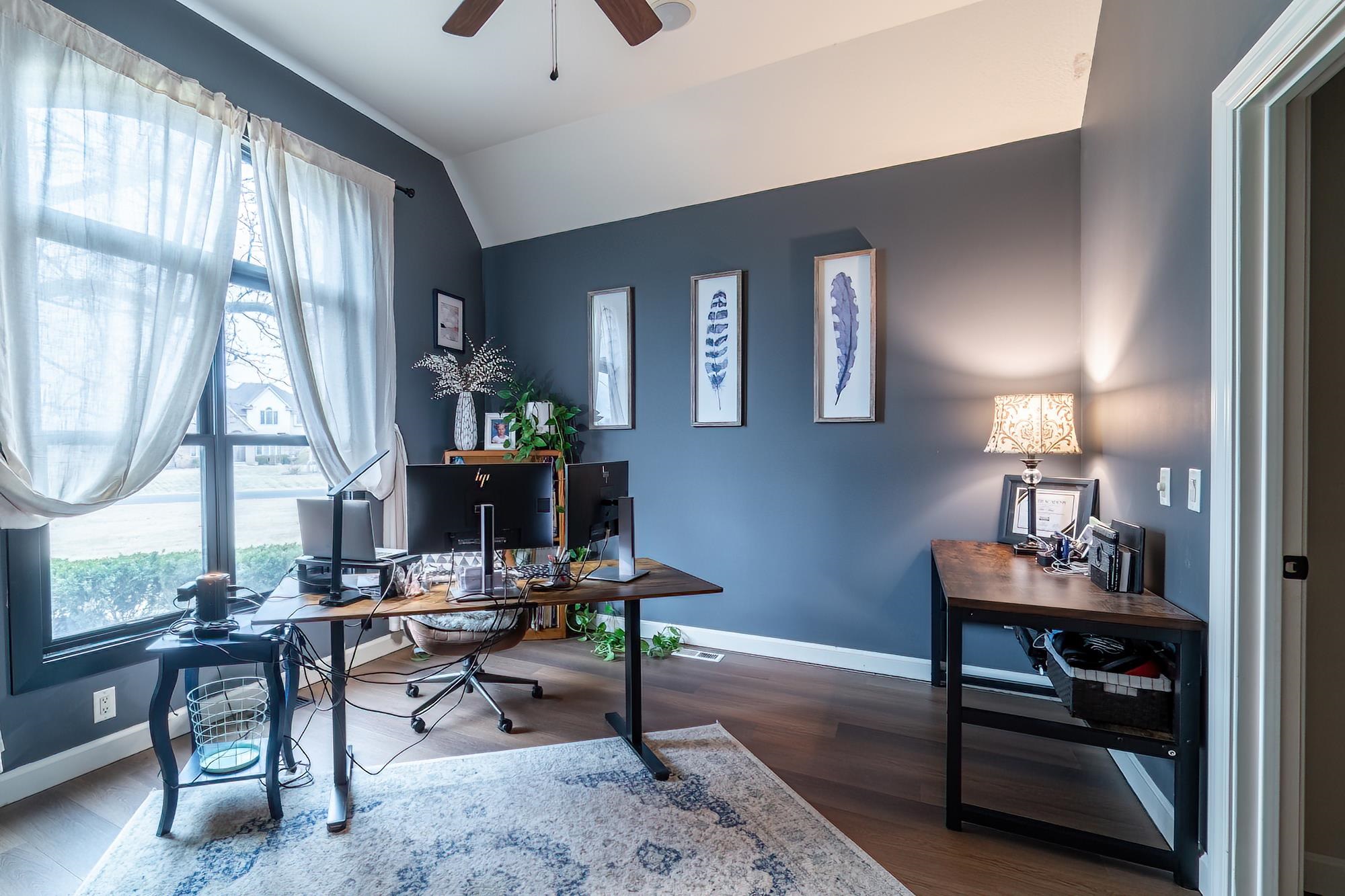 Office space with ceiling fan, dark wood-style flooring, and lofted ceiling