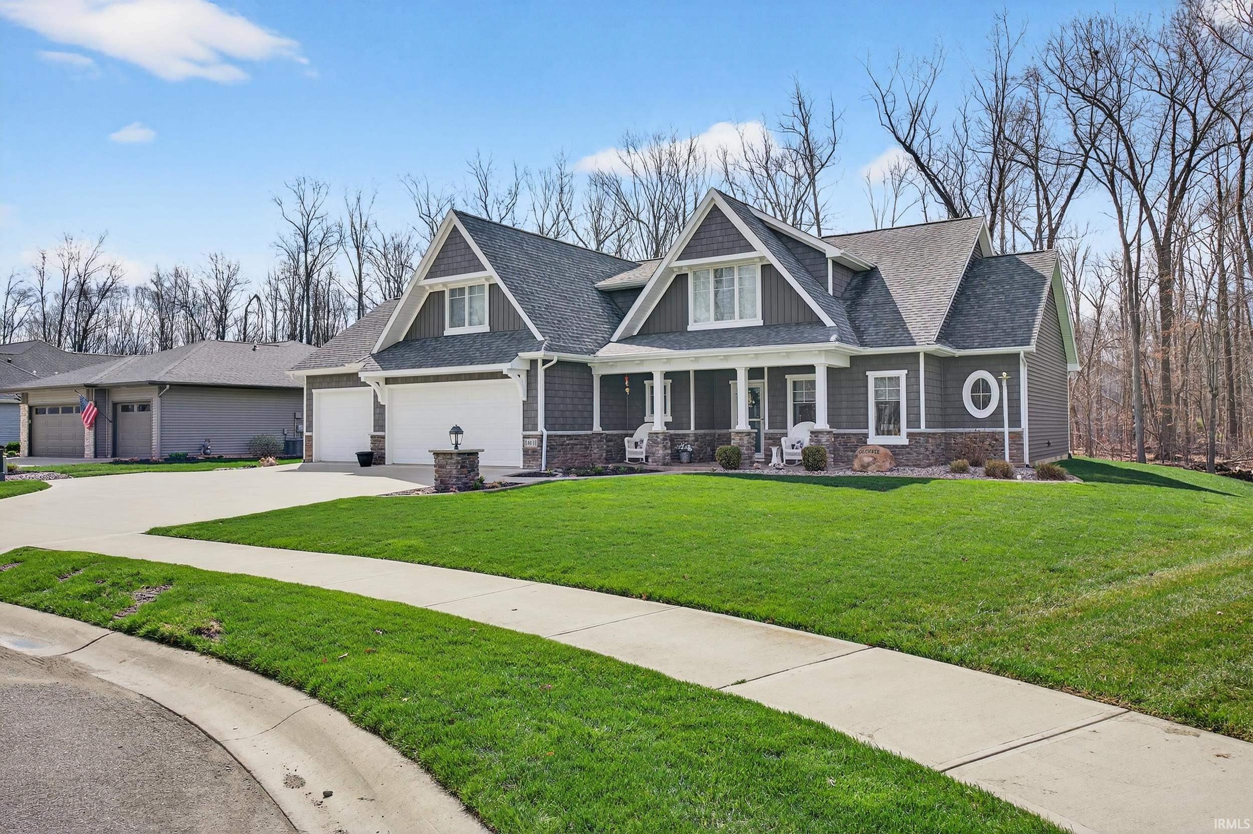 Craftsman-style home featuring a porch, stone siding, concrete driveway, roof with shingles, and a front lawn