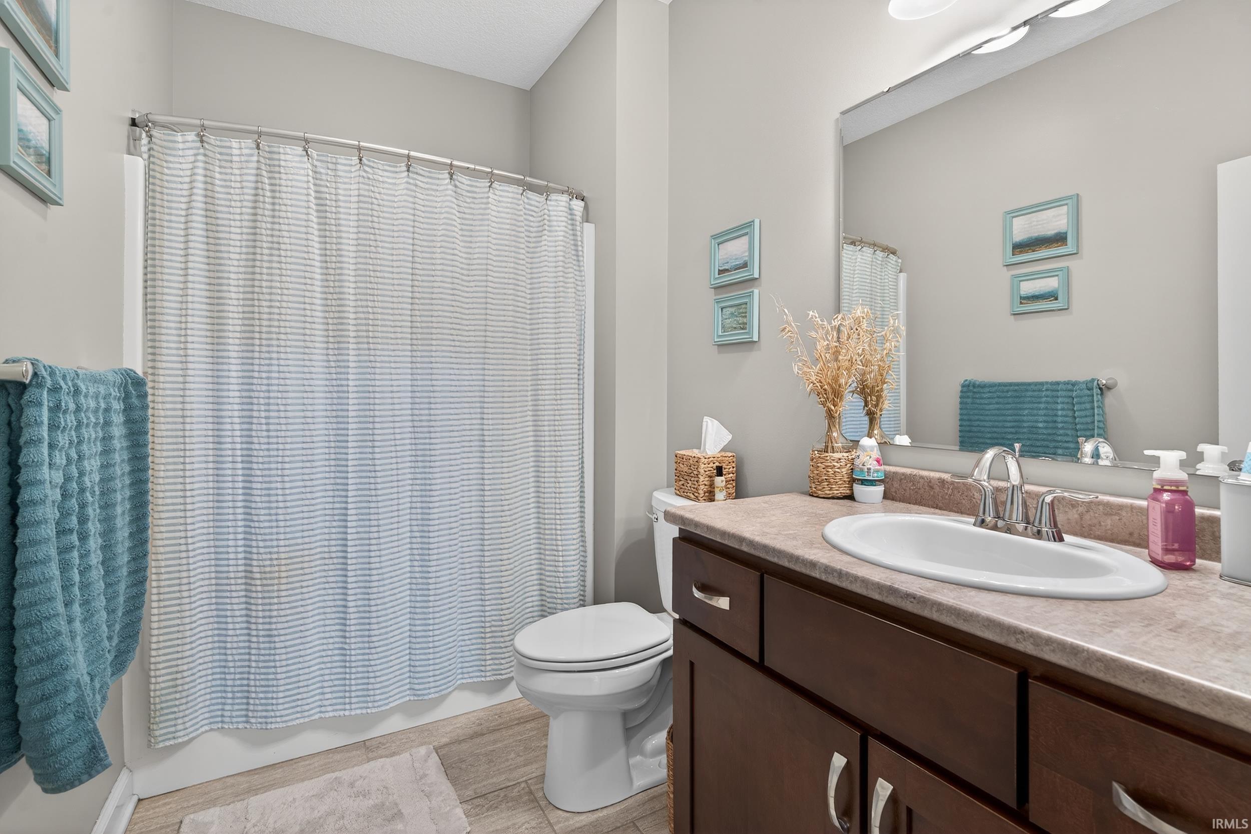 Bathroom with vanity, shower / bath combination with curtain, and light wood-type flooring