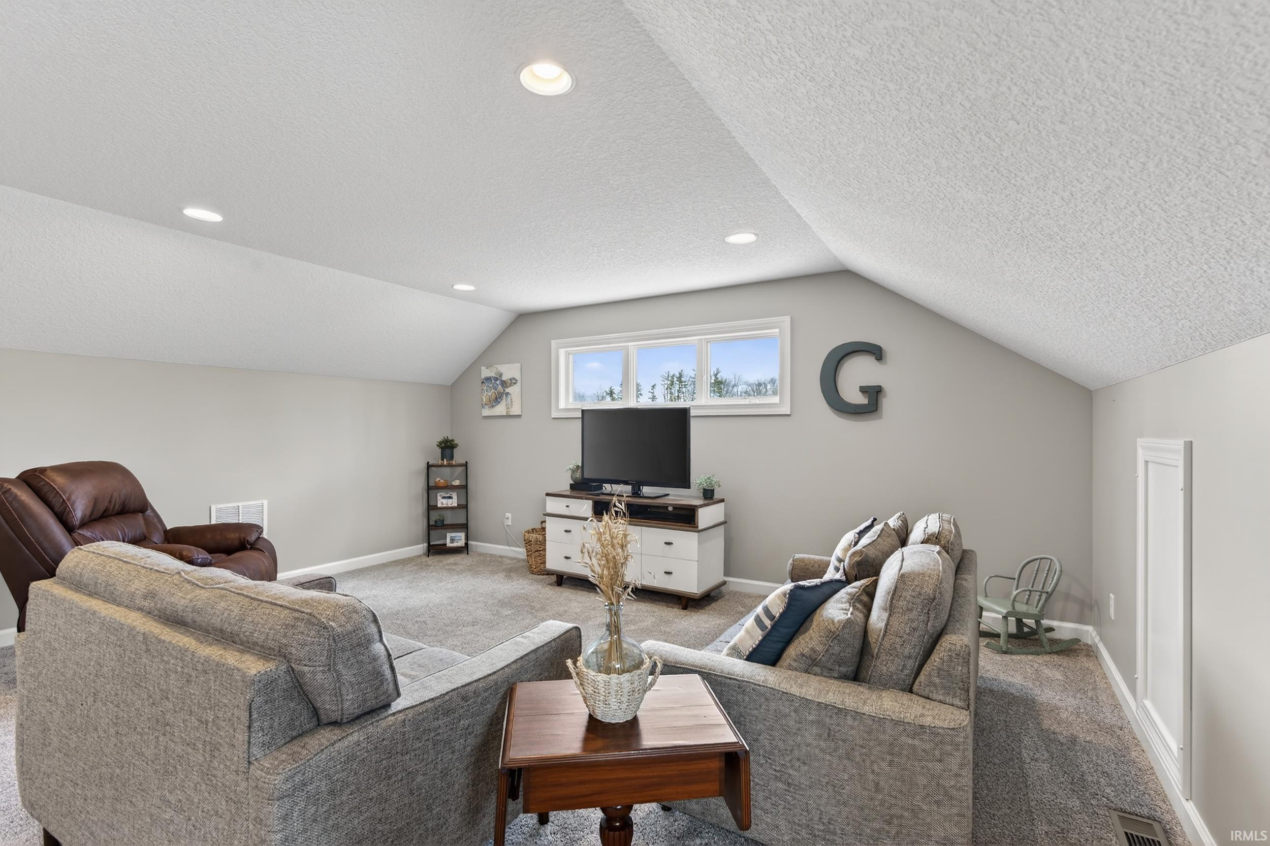 Living area featuring a textured ceiling and carpet flooring
