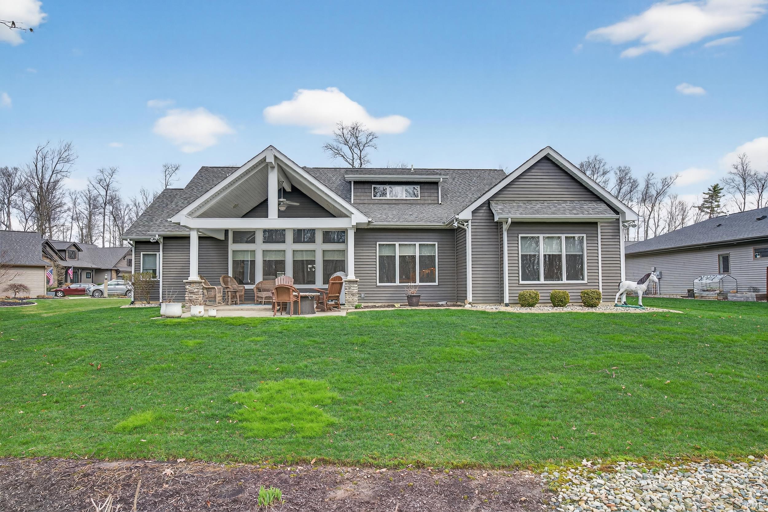 Back of property with a shingled roof, a patio area, and a yard