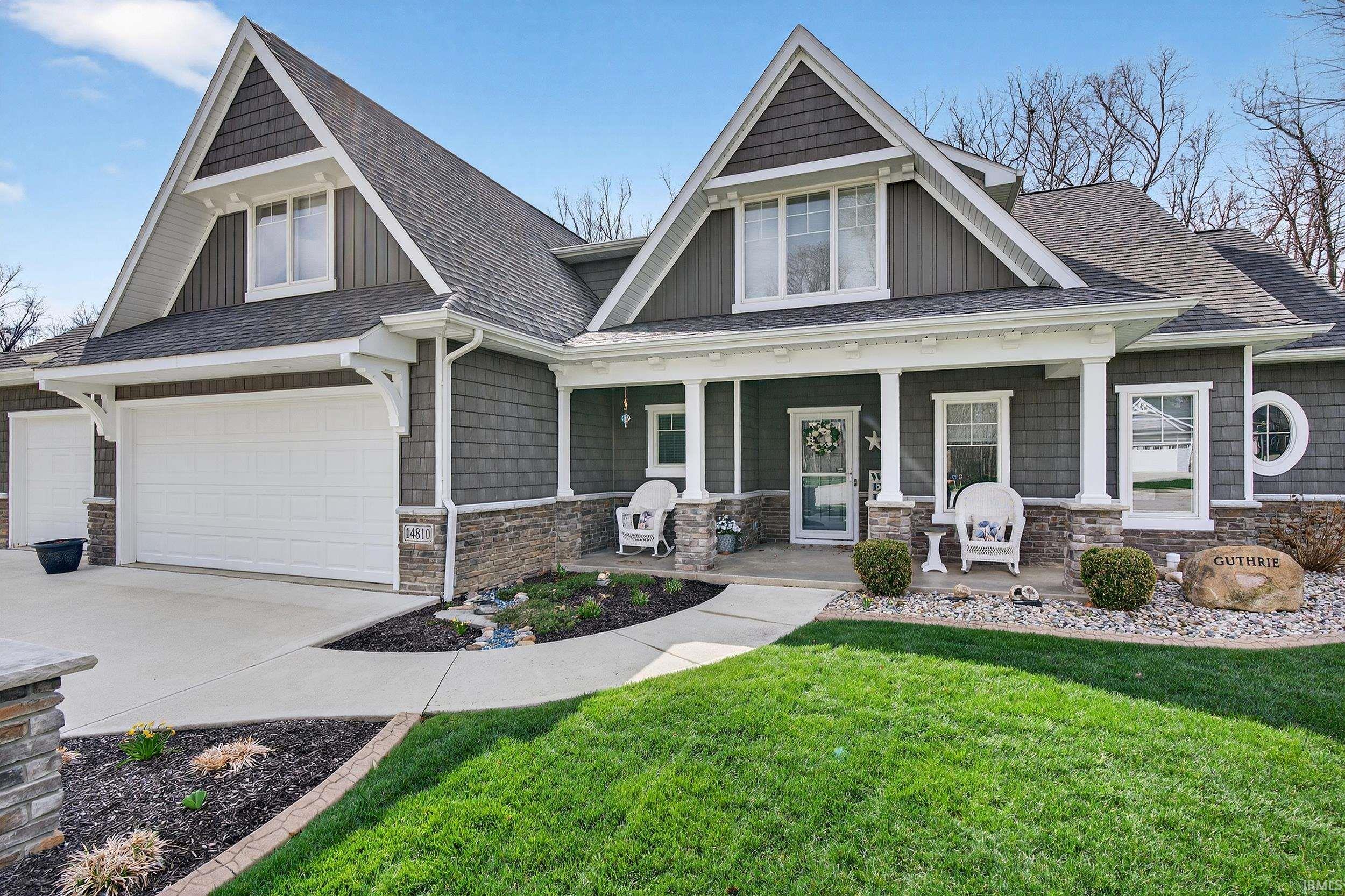 Craftsman inspired home featuring stone siding, covered porch, a front lawn, board and batten siding, and roof with shingles
