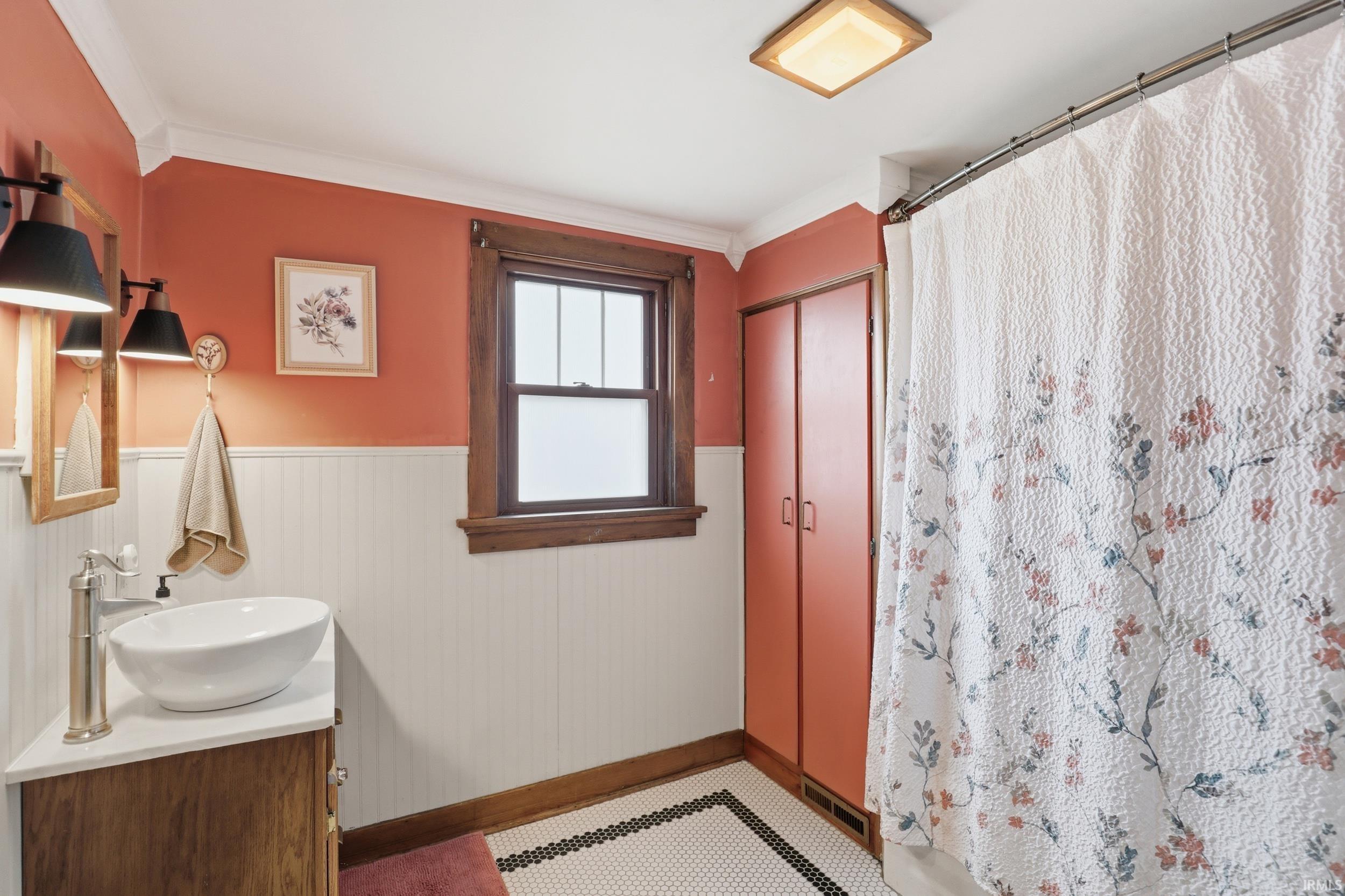 Bathroom featuring a shower with shower curtain, wainscoting, and vanity