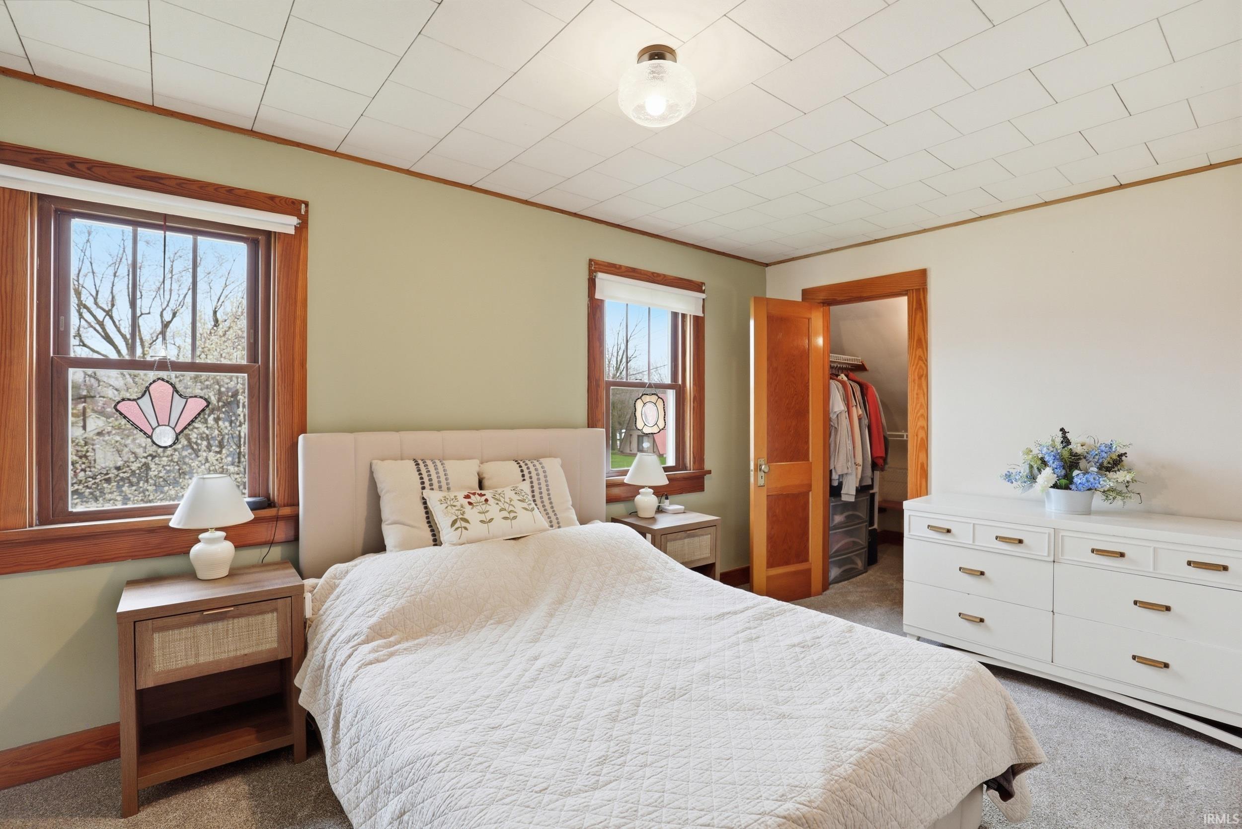 Bedroom with a walk in closet, dark carpet, and crown molding