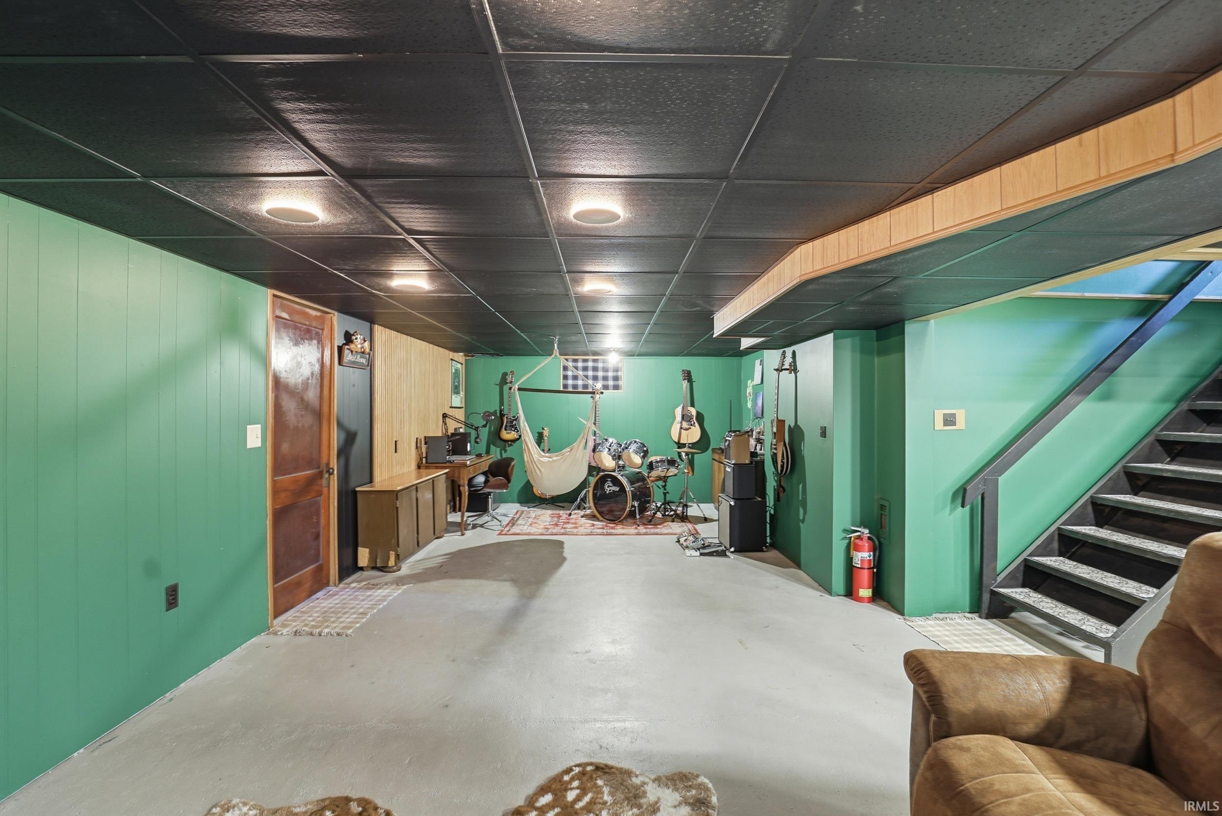 Finished basement featuring wood walls and a drop ceiling