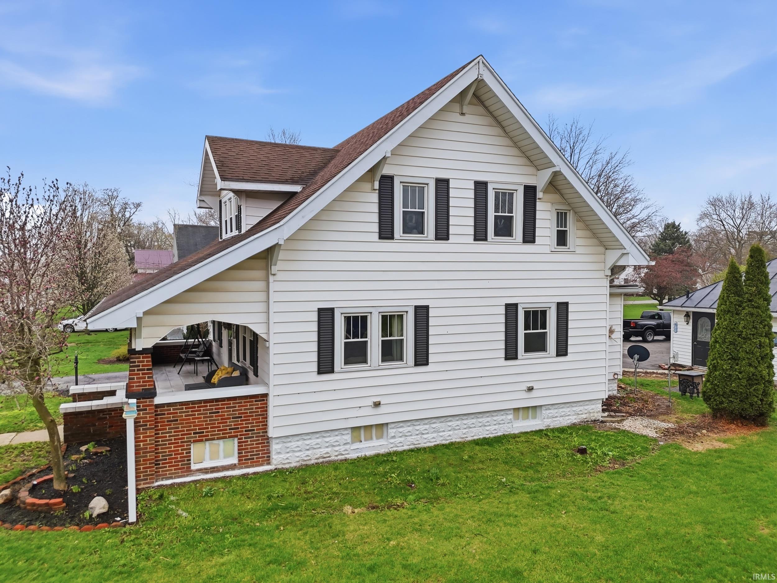View of side of home with a lawn and roof with shingles