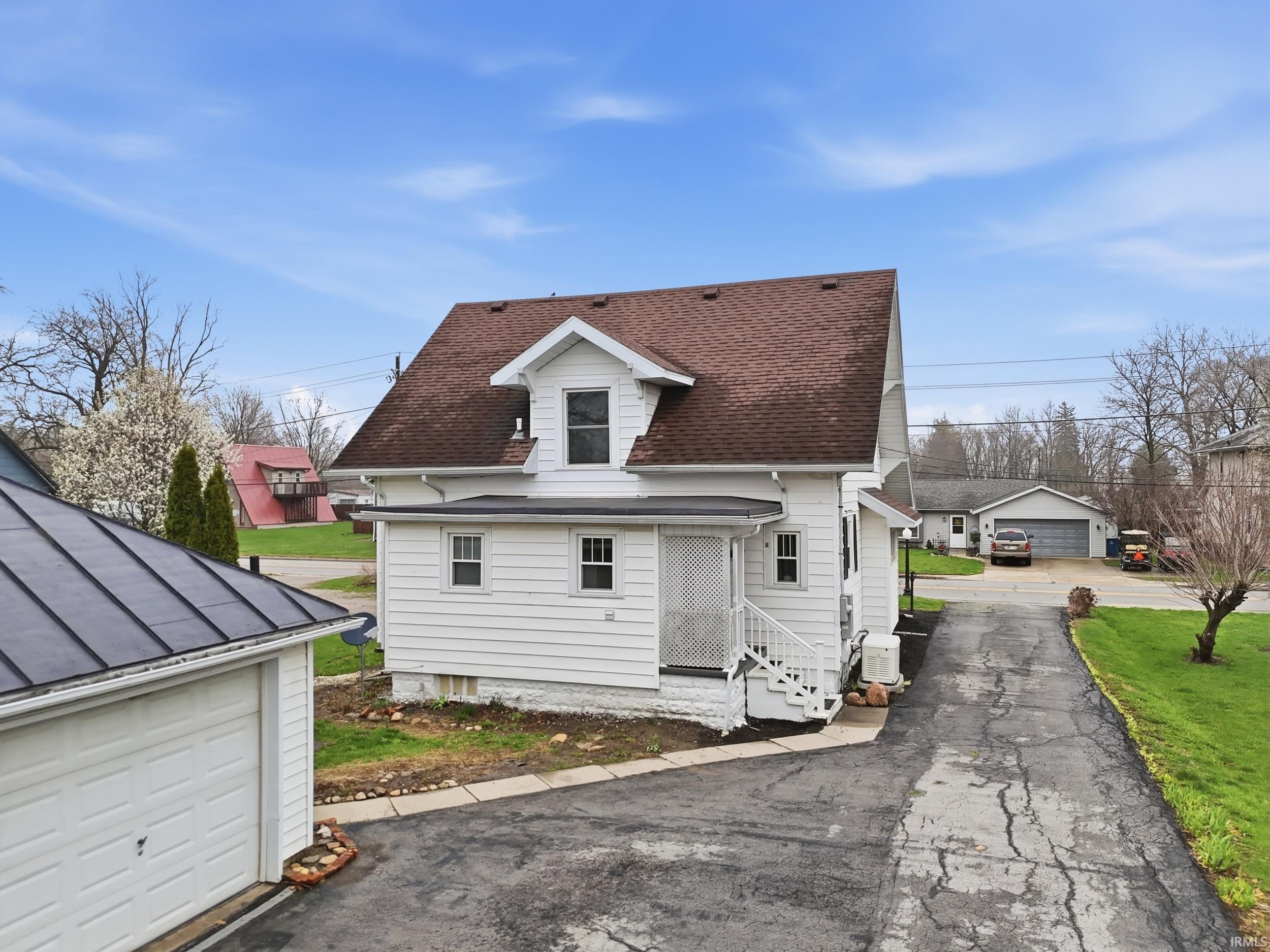 Rear view of property featuring an outbuilding, roof with shingles, and a garage