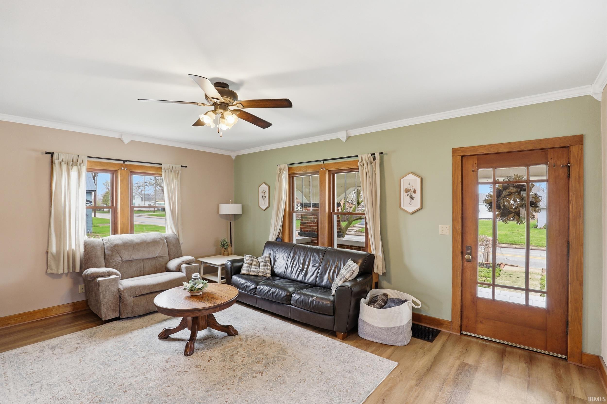 Living area featuring ceiling fan, light wood-style floors, and ornamental molding
