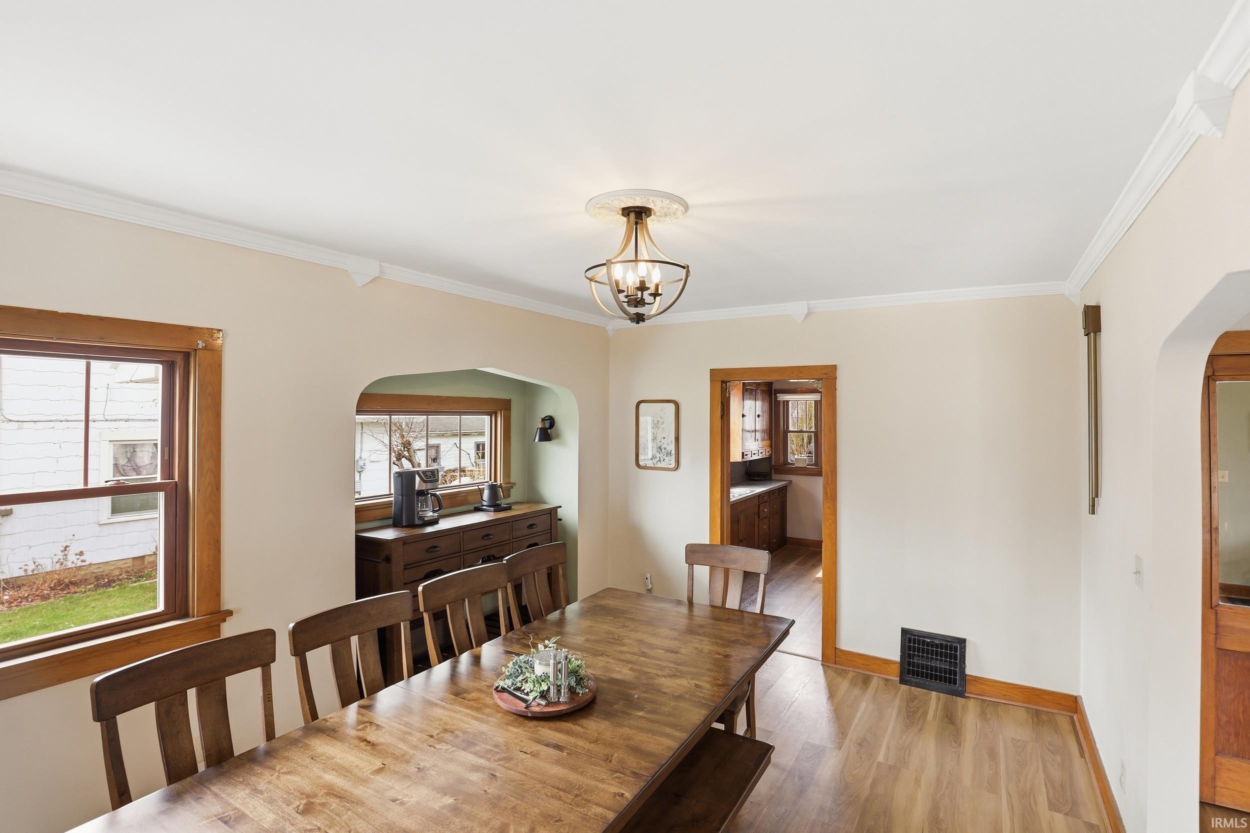 Dining area featuring arched walkways, wood finished floors, ornamental molding, and hanging lights