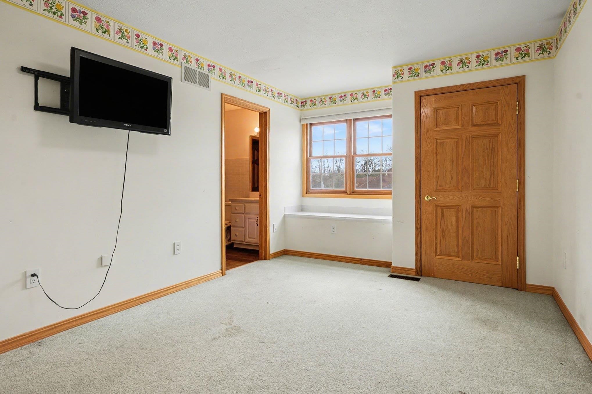 Unfurnished bedroom with light colored carpet and ensuite bathroom