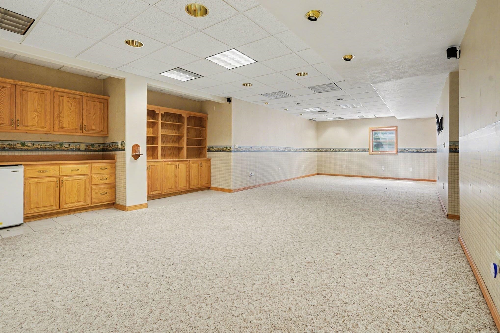 Empty room featuring wainscoting, a drop ceiling, and tile walls