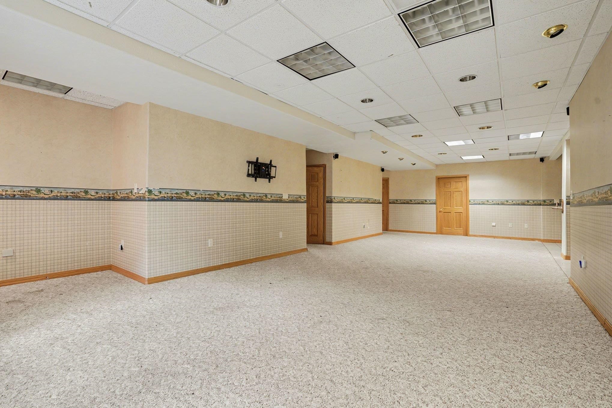 Spare room with wainscoting, a drop ceiling, and light carpet
