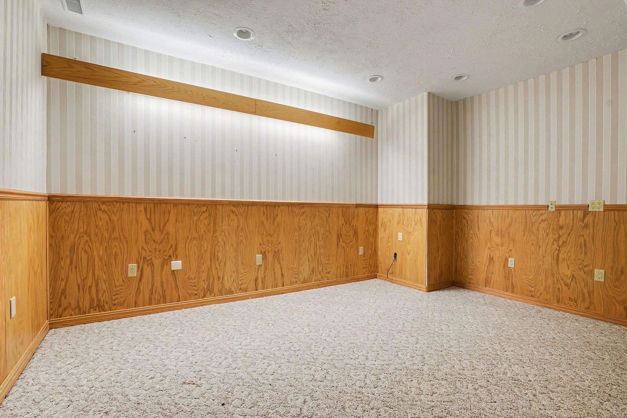 Unfurnished room featuring wooden walls, a textured ceiling, wainscoting, wallpapered walls, and recessed lighting