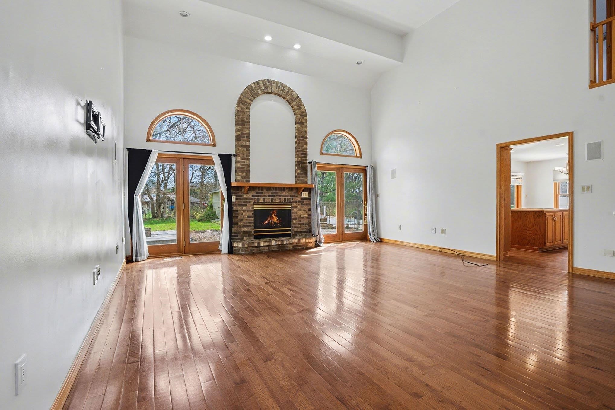 Unfurnished living room featuring french doors, hardwood / wood-style flooring, recessed lighting, a fireplace, and a high ceiling