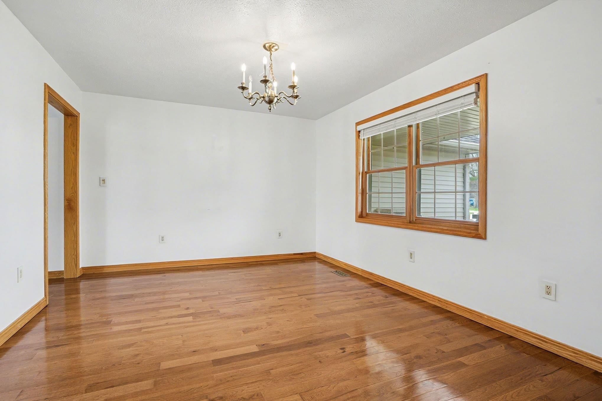 Unfurnished room featuring light wood finished floors and hanging lights