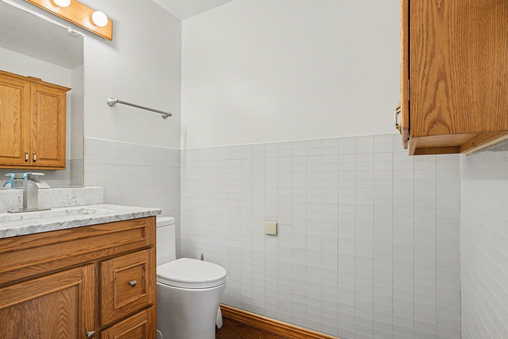 Bathroom with vanity, tile walls, and a wainscoted wall