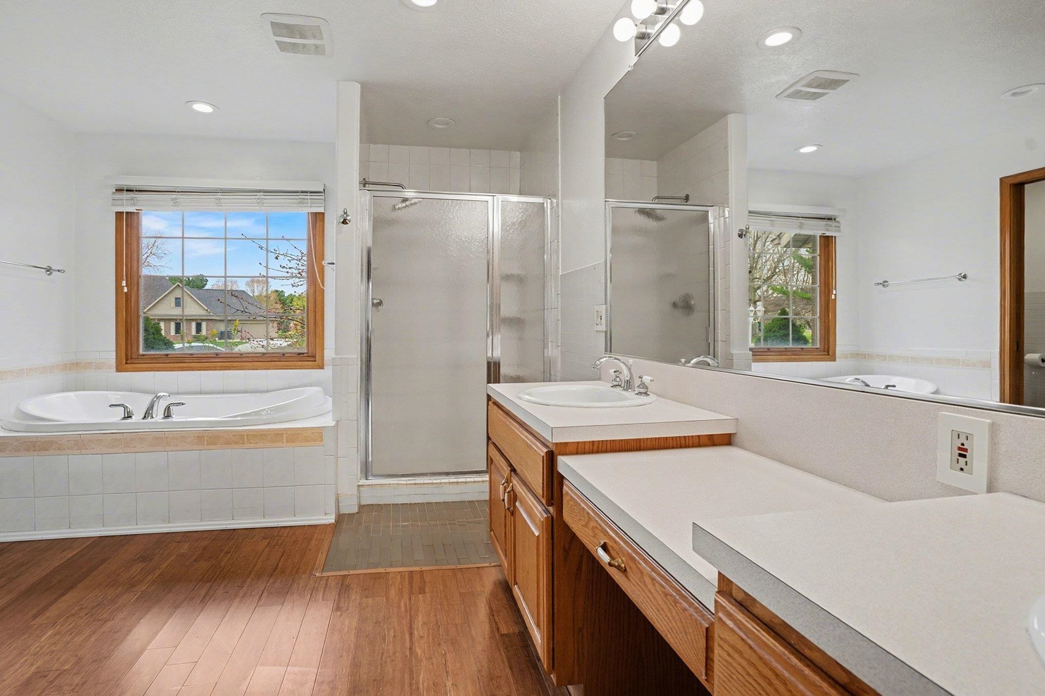 Full bath with a garden tub, vanity, a stall shower, dark wood-style floors, and recessed lighting