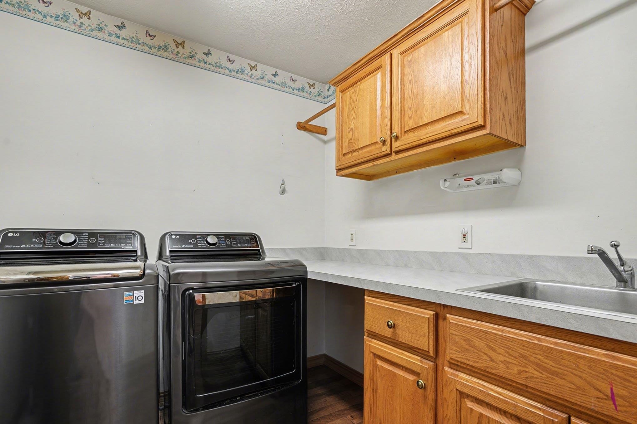 Laundry room with washer and dryer, cabinet space, a textured ceiling, and wood finished floors
