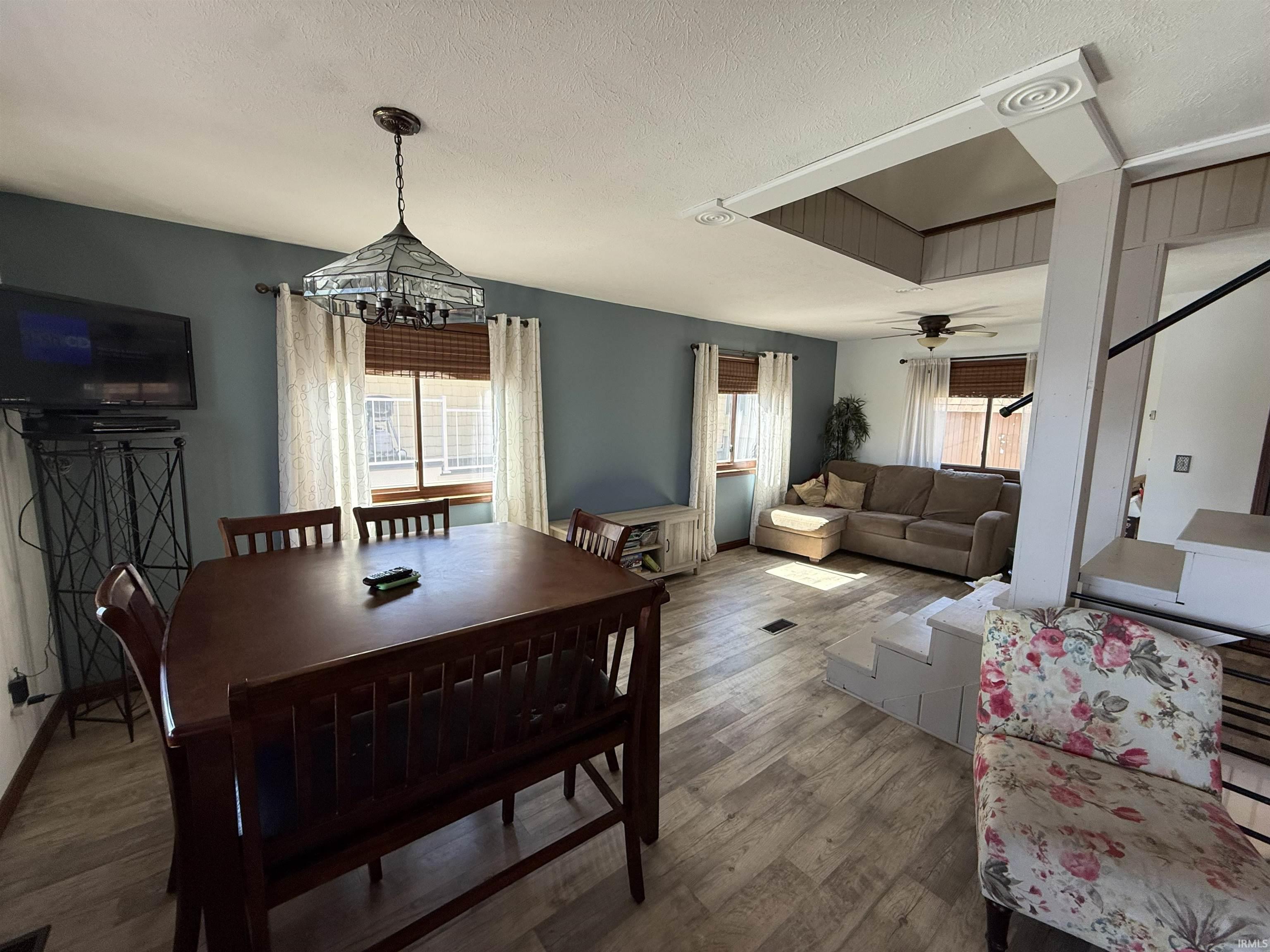 Dining space featuring wood finished floors, a textured ceiling, and ceiling fan