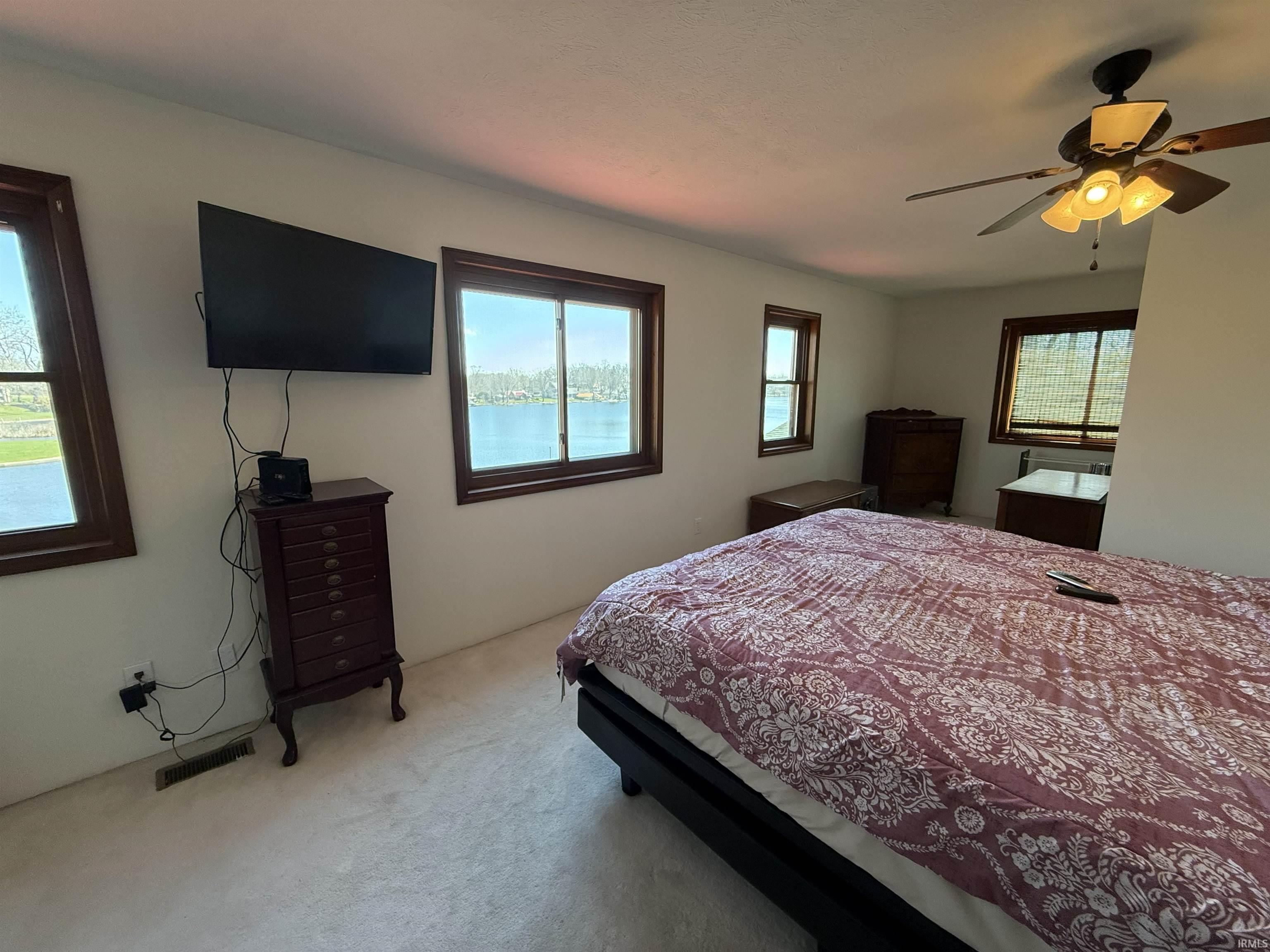 Bedroom featuring multiple windows, light carpet, and ceiling fan