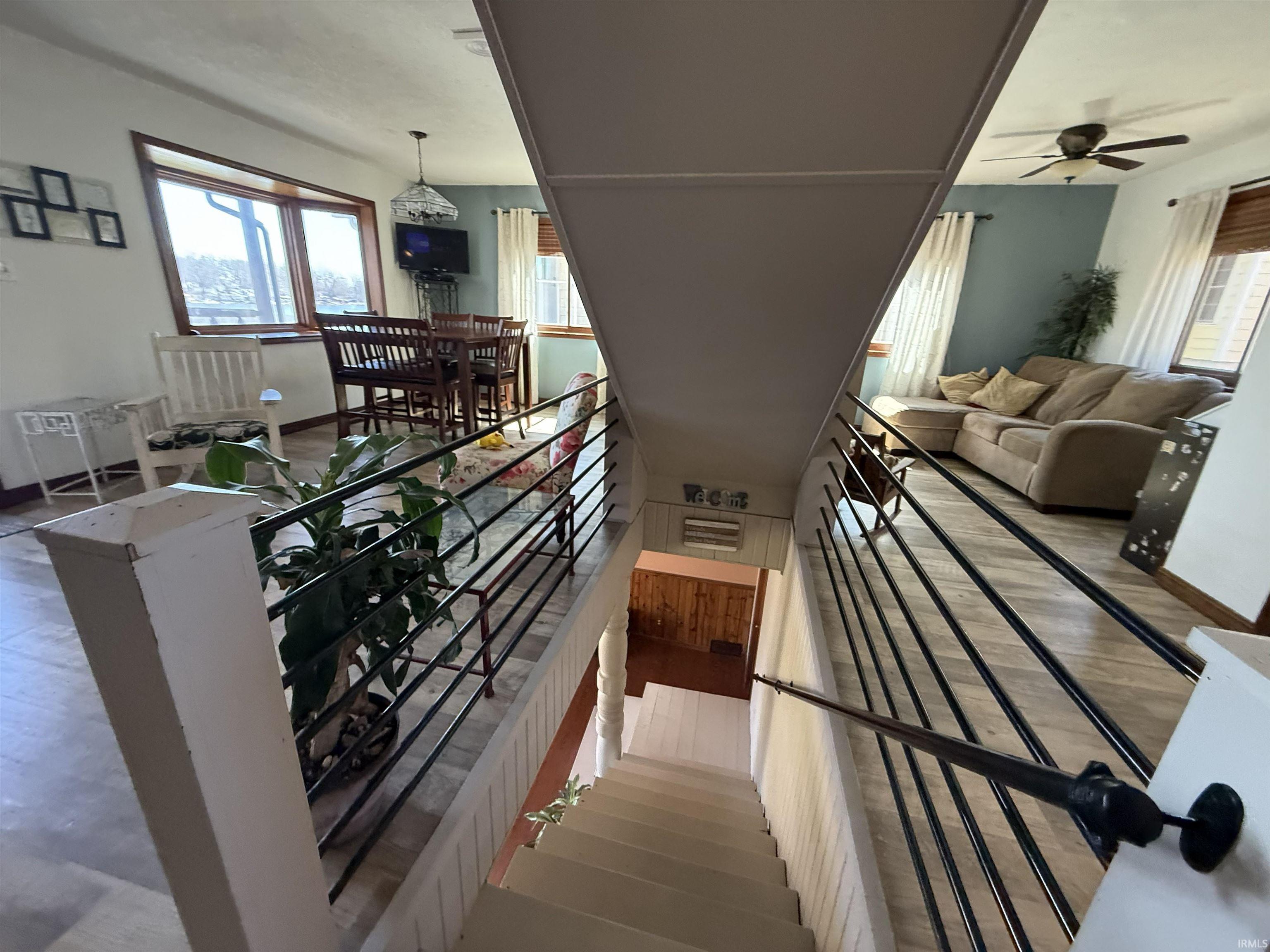 Stairway with ceiling fan, plenty of natural light, and wood finished floors