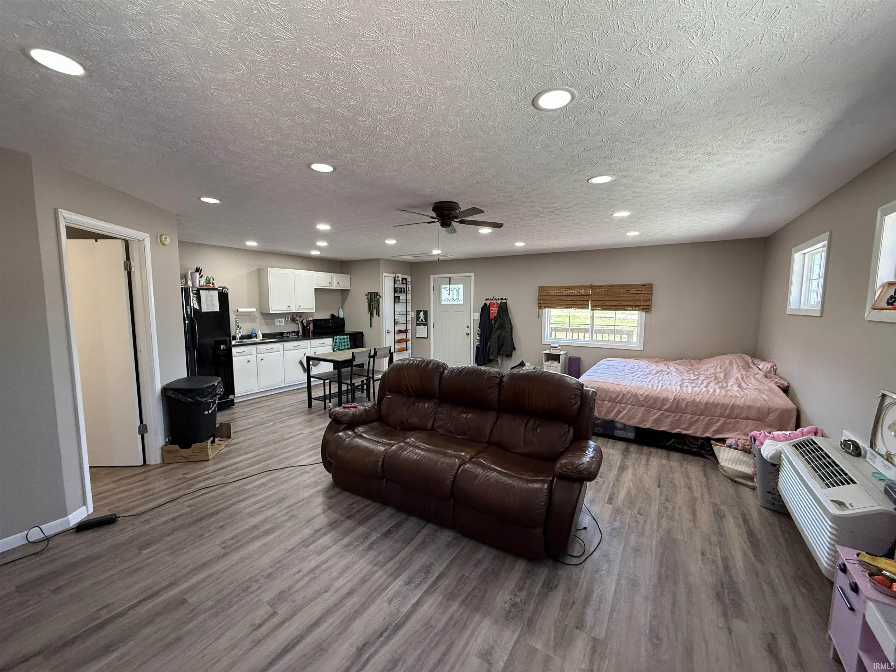 Bedroom featuring freestanding refrigerator, wood finished floors, recessed lighting, and a textured ceiling