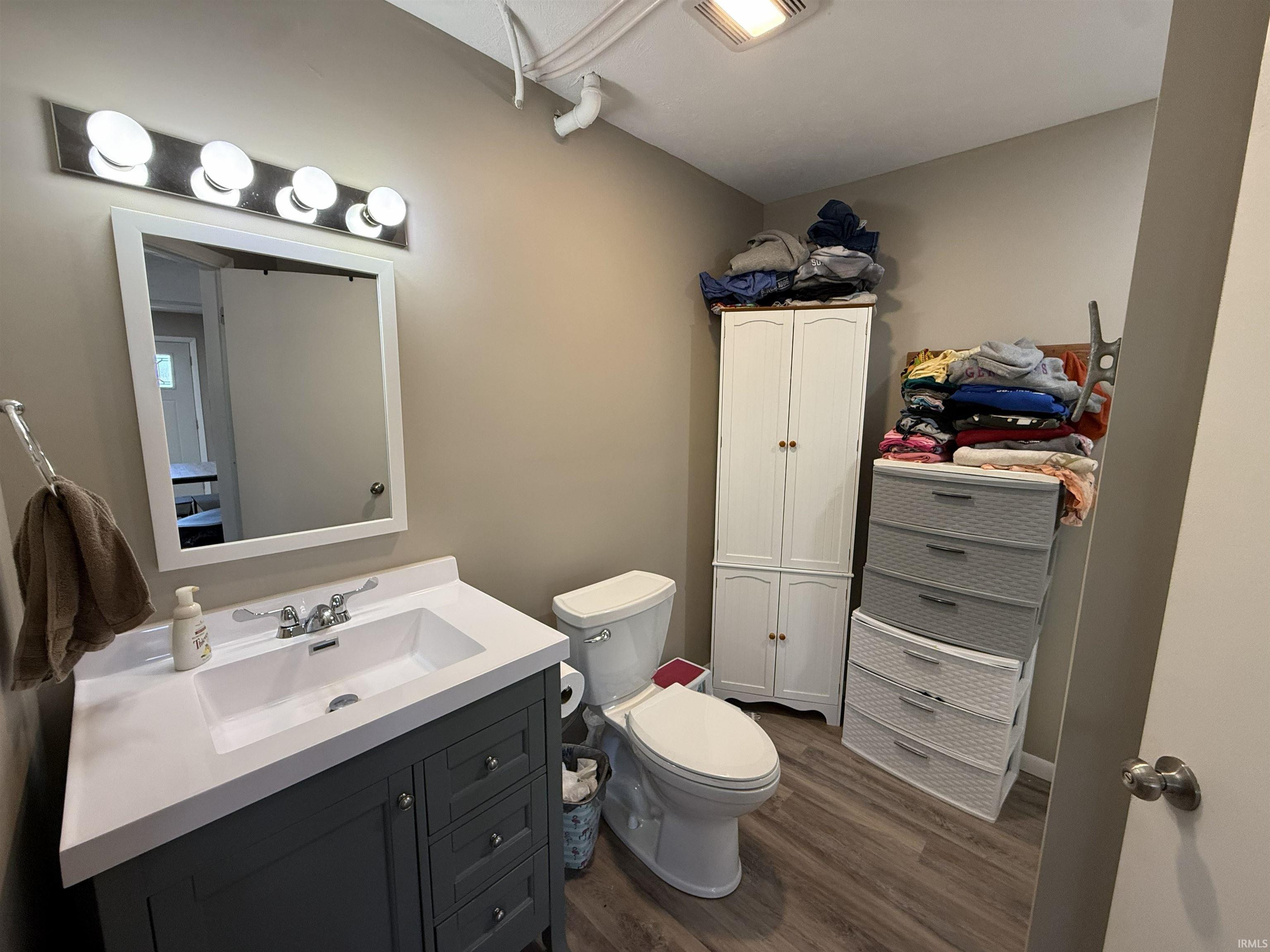 Half bath with vanity, dark wood finished floors, and a closet