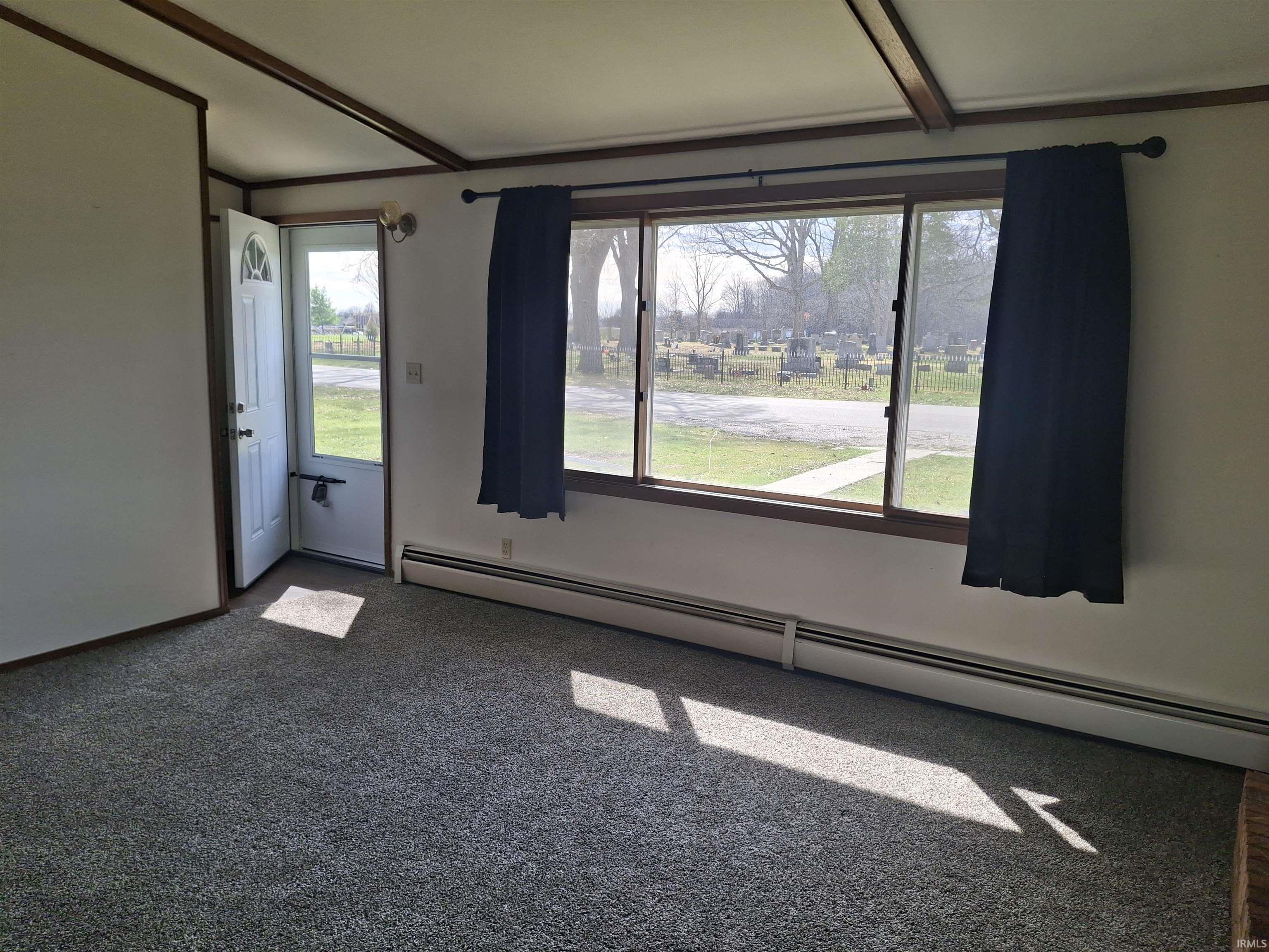 Carpeted spare room featuring a baseboard radiator