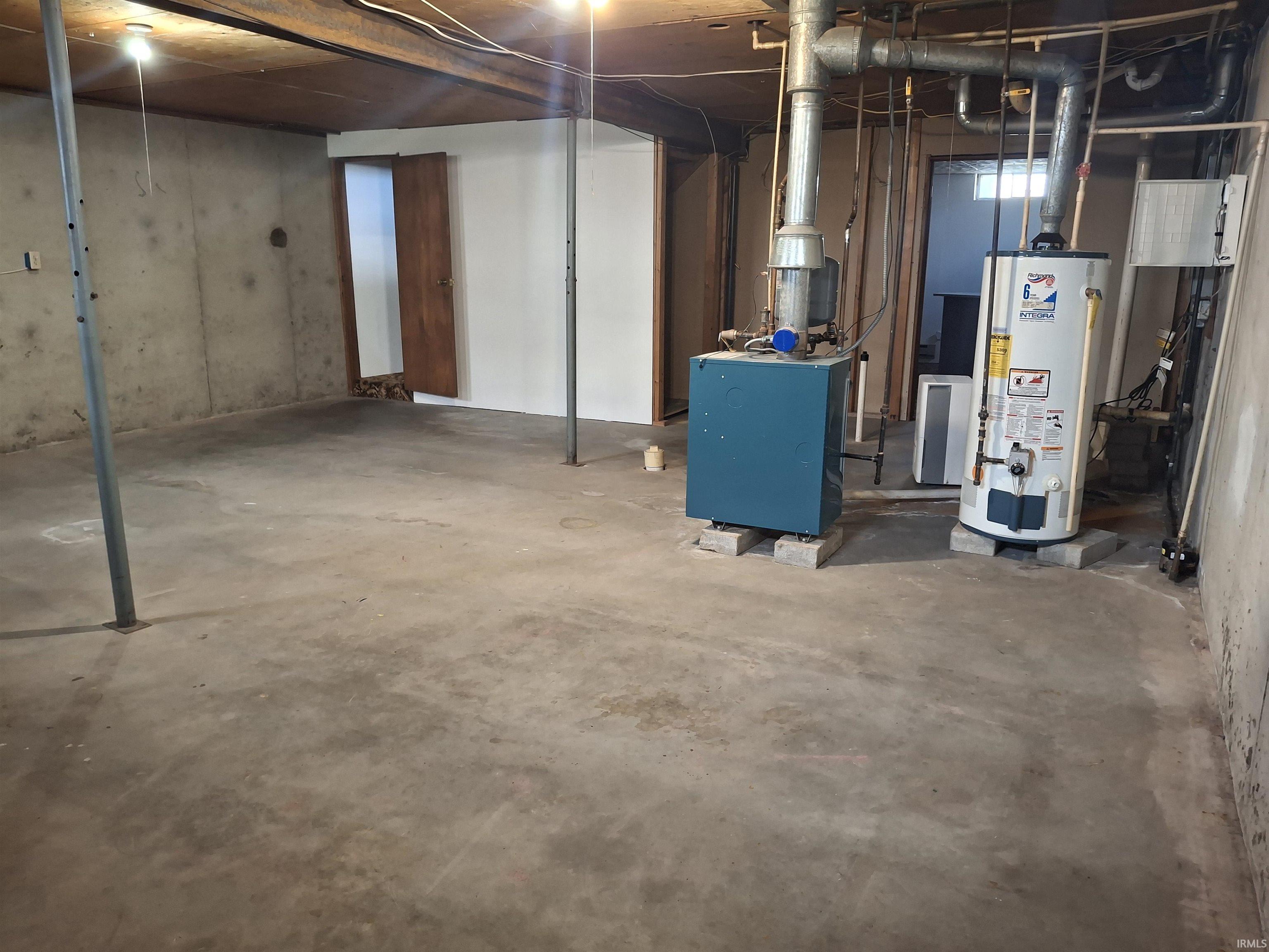 Unfinished below grade area featuring water heater and a heating unit