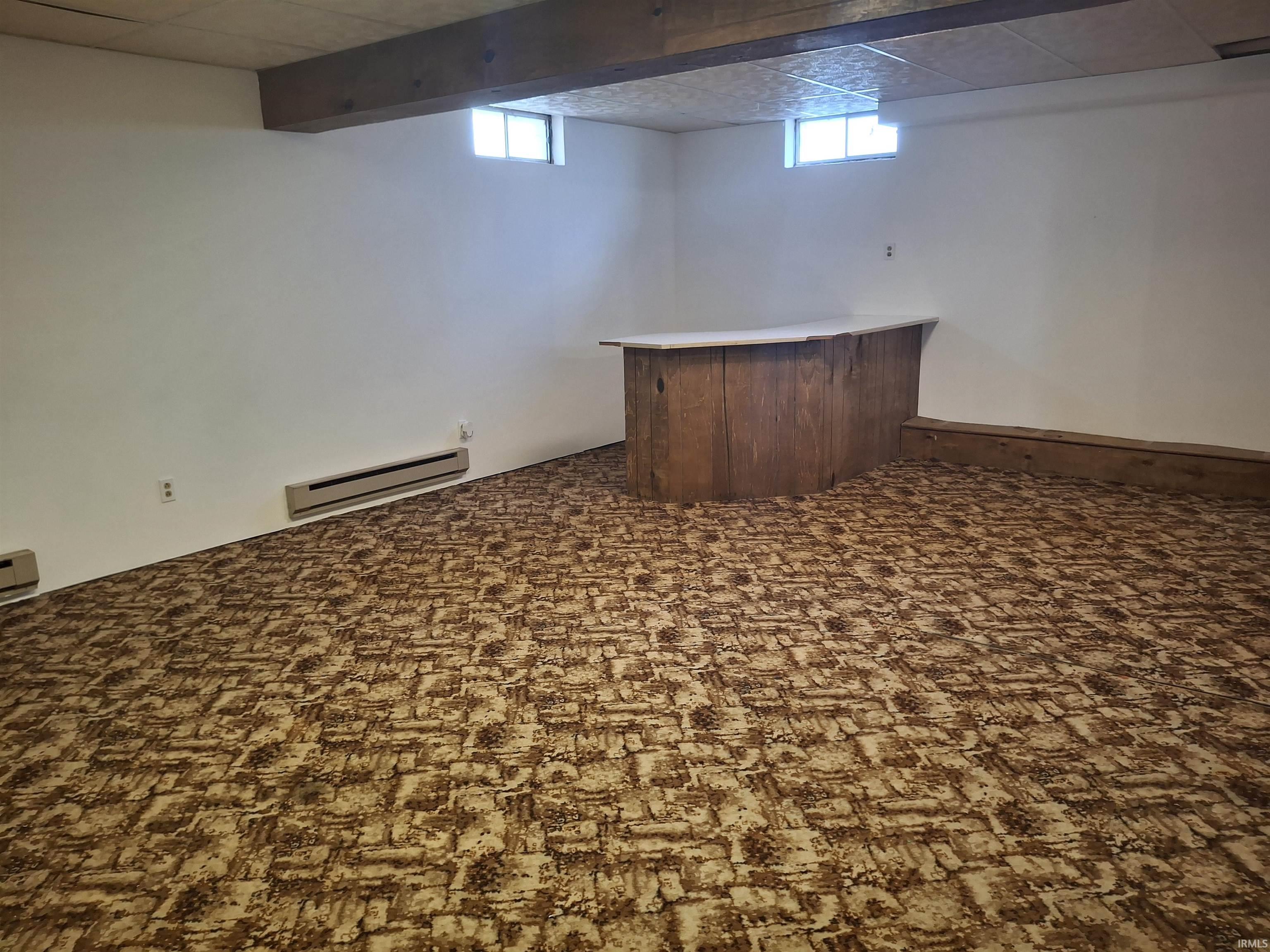 Indoor dry bar featuring baseboard heating, plenty of natural light, light countertops, and dark carpet