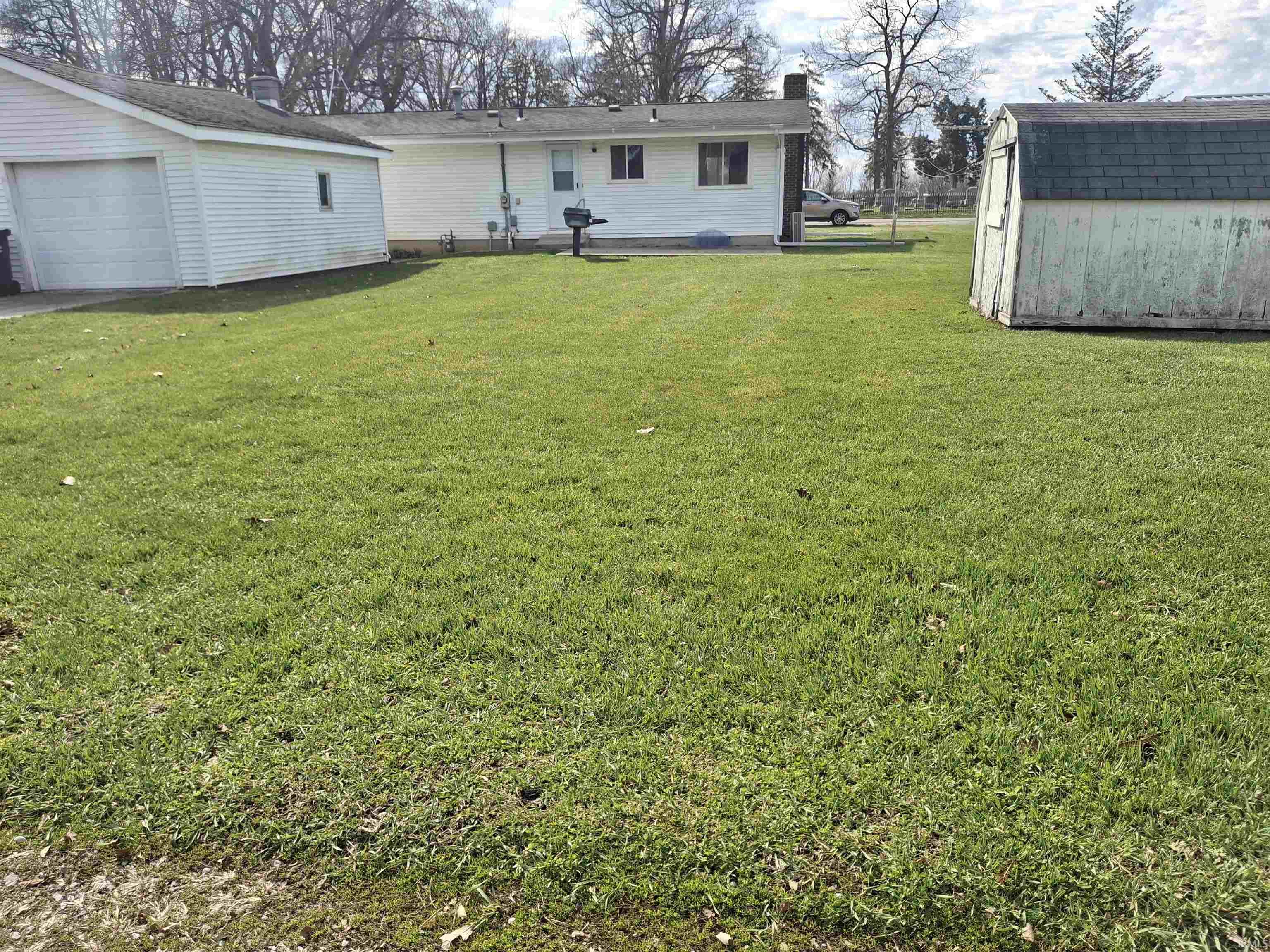View of green lawn with a storage unit and a detached garage