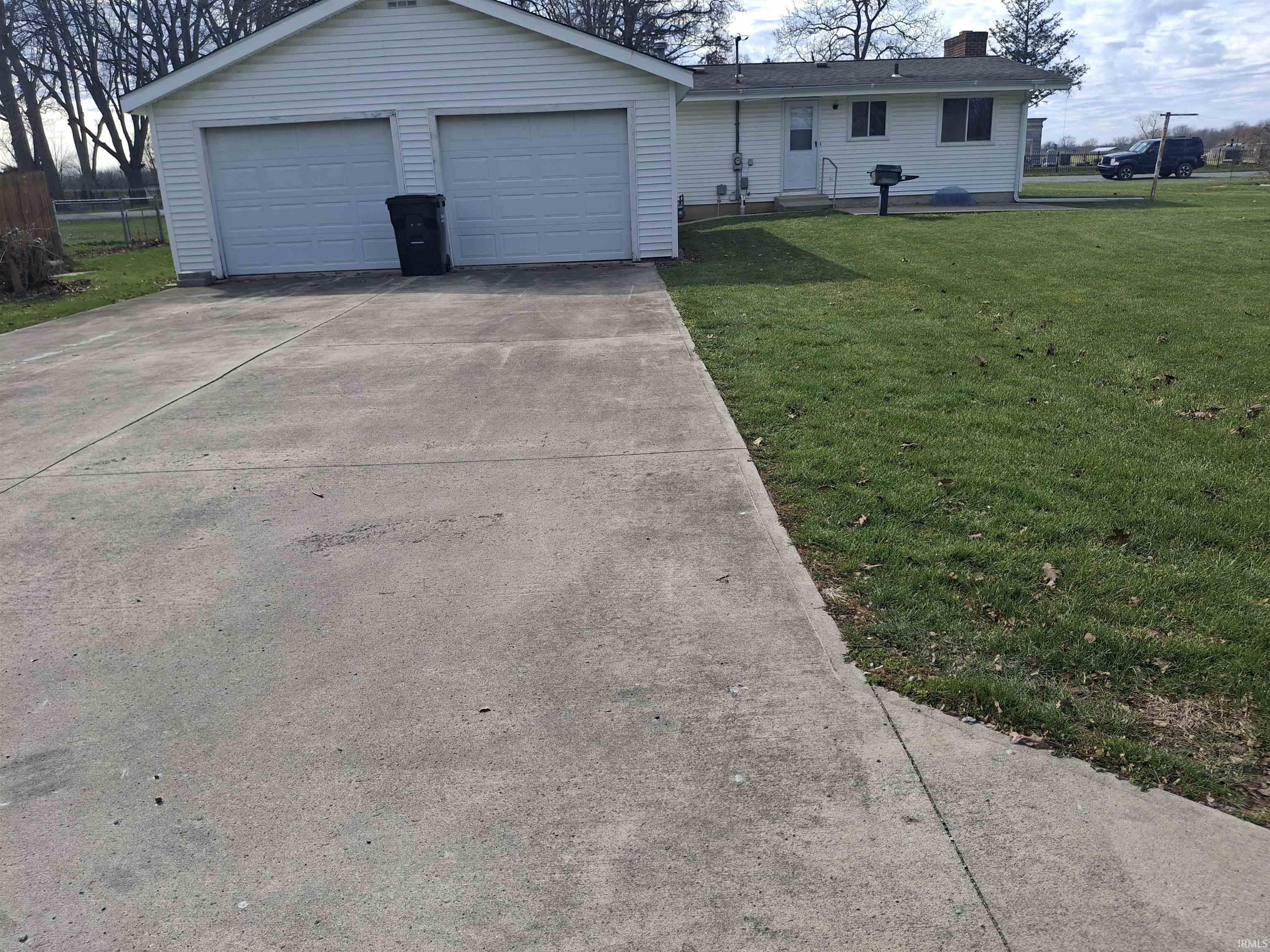 View of front of home featuring a garage, a chimney, an outdoor structure, and concrete driveway