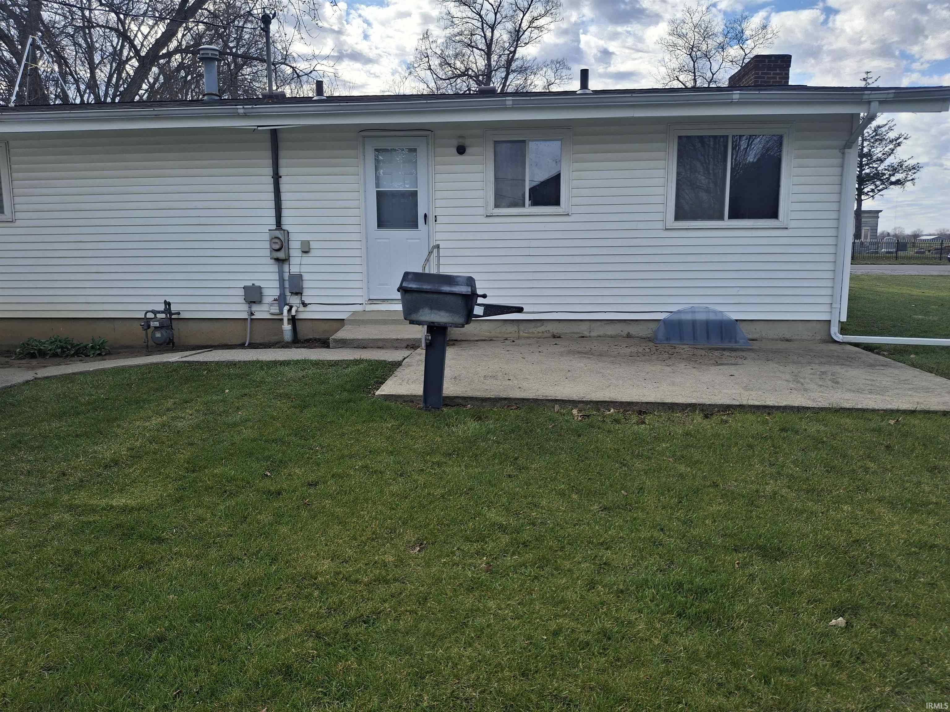 View of front facade with a front lawn, a chimney, and a patio