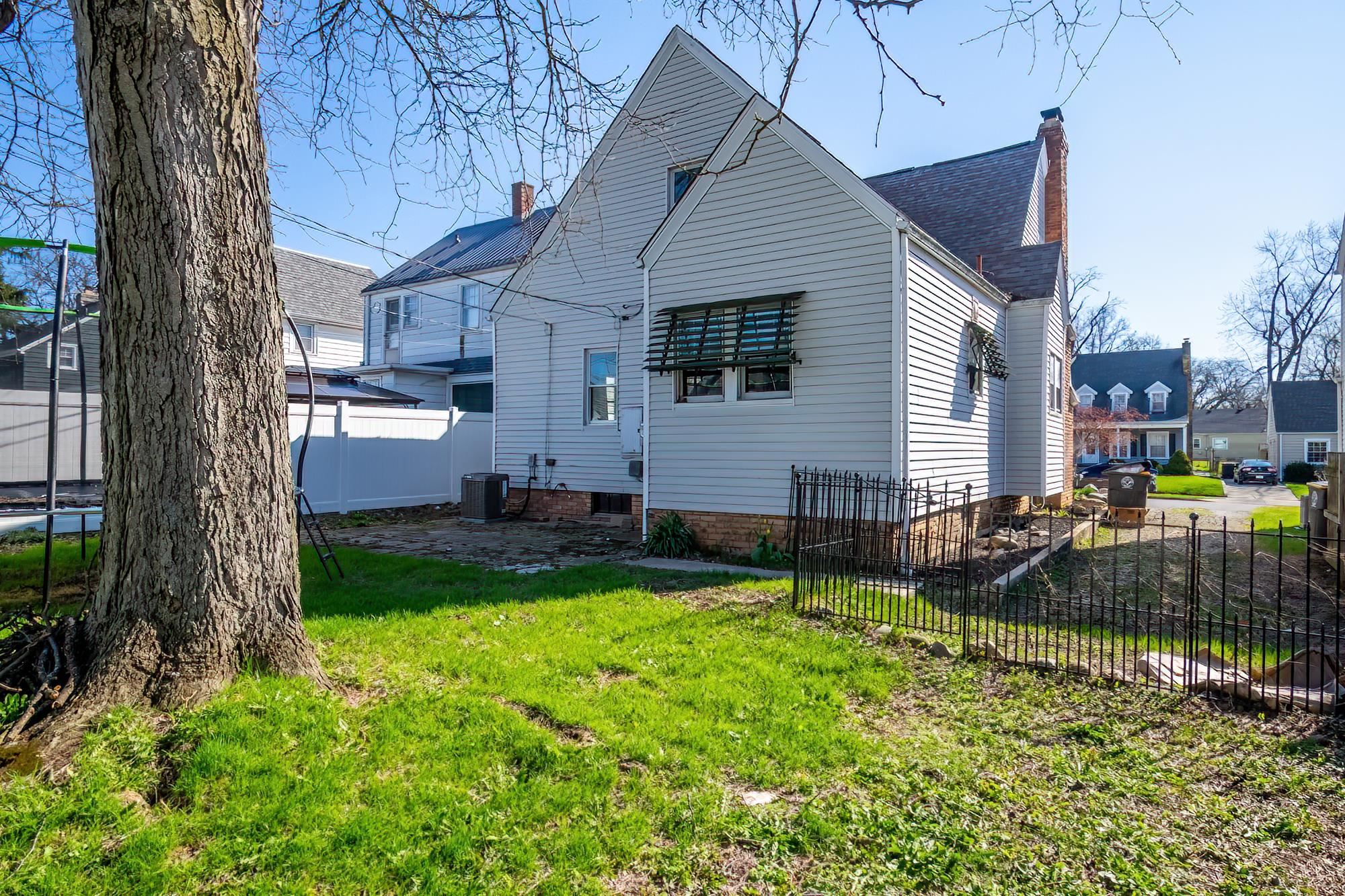 Rear view of house featuring a patio area, a fenced backyard, a chimney, and roof with shingles