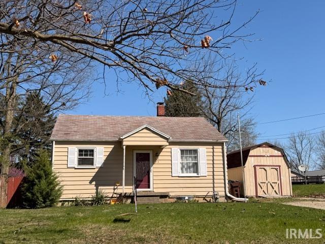 Bungalow-style house with a front yard, a storage shed, and a chimney