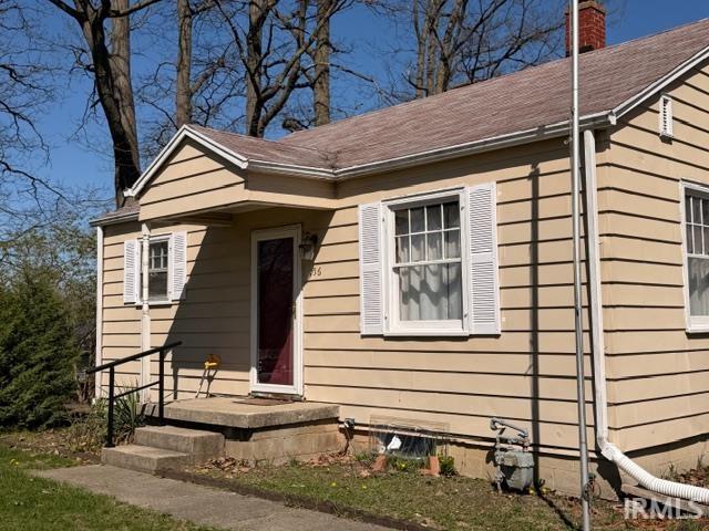 View of front facade featuring a chimney and a shingled roof