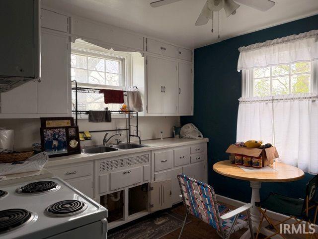 Kitchen with white cabinetry, white electric stove, and light countertops