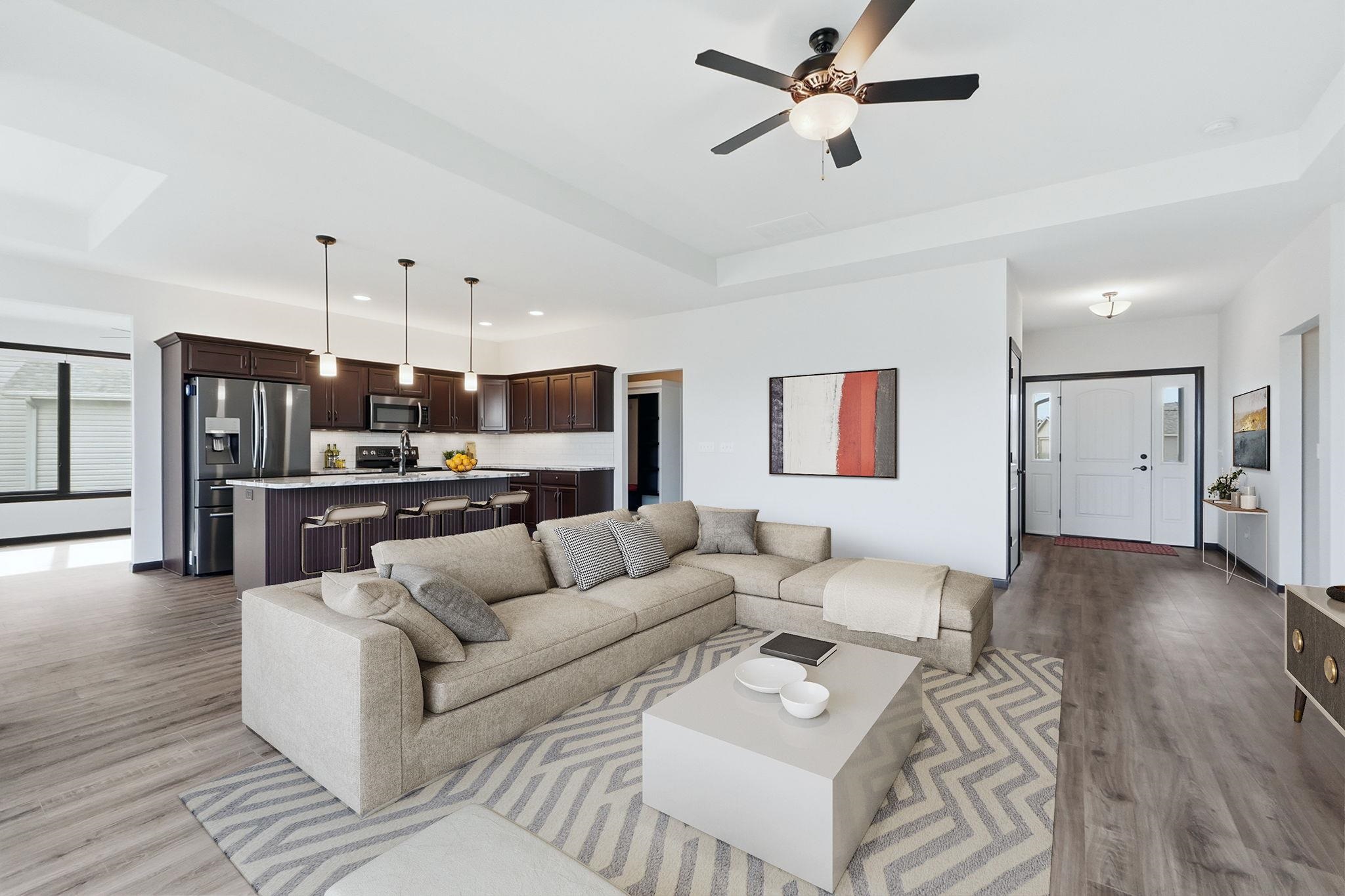 Living room featuring ceiling fan, light wood-style floors, recessed lighting, and a tray ceiling