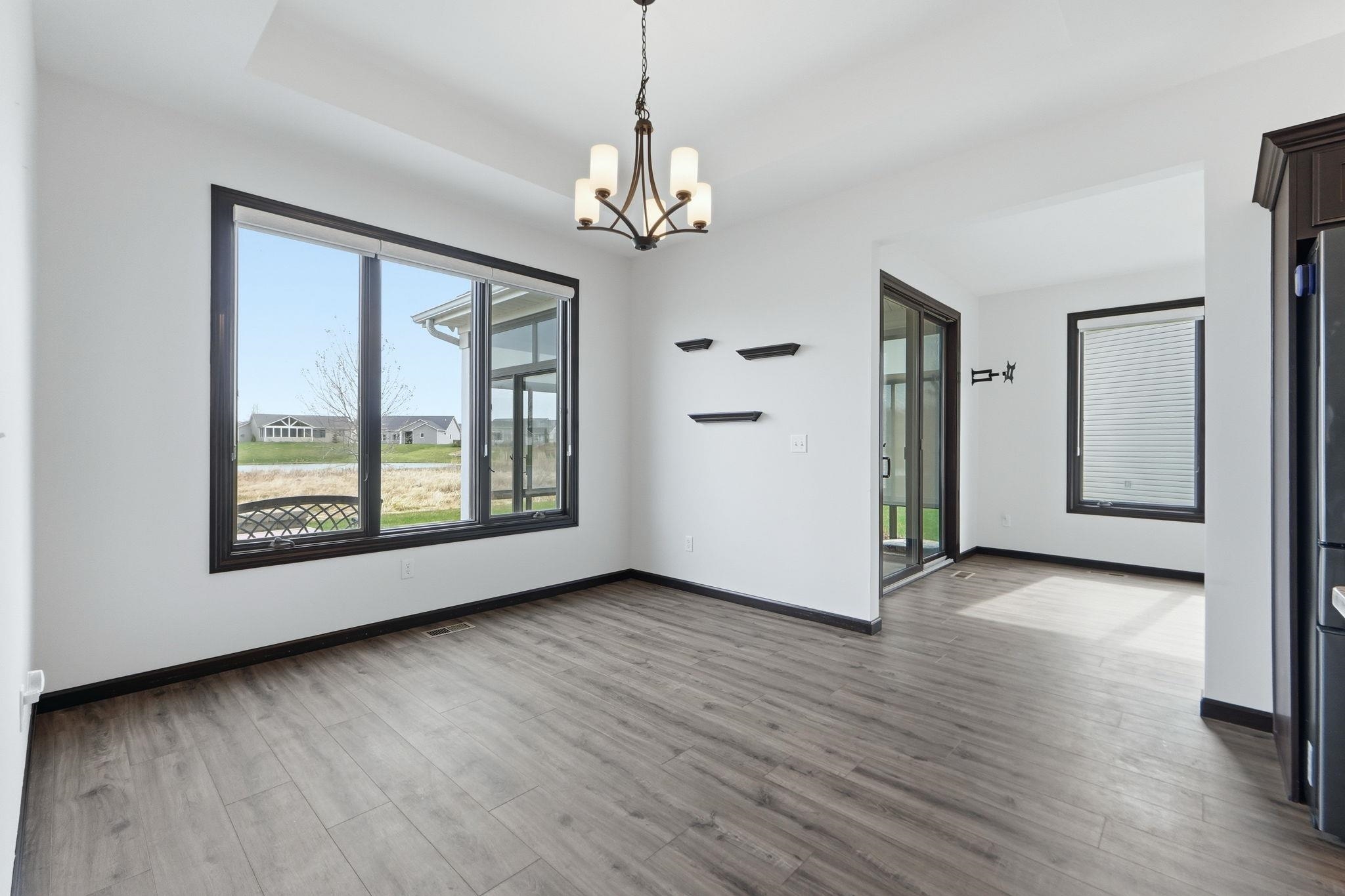 Empty room featuring a chandelier, light wood finished floors, and a tray ceiling
