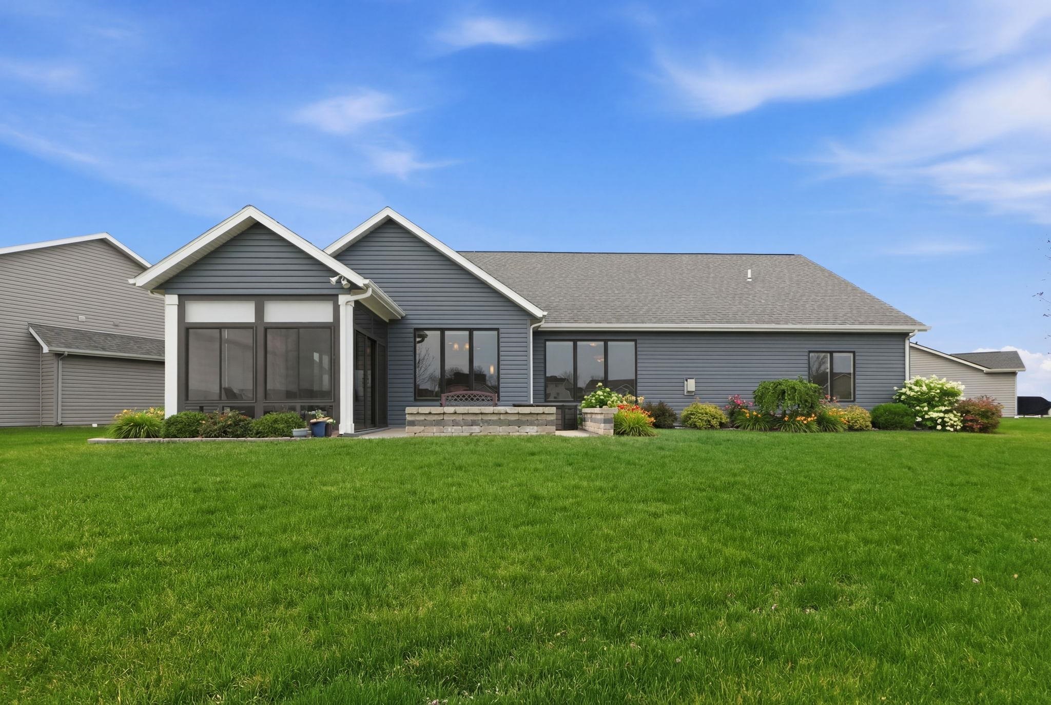 Rear view of house with a yard, a shingled roof, a sunroom, and a patio area