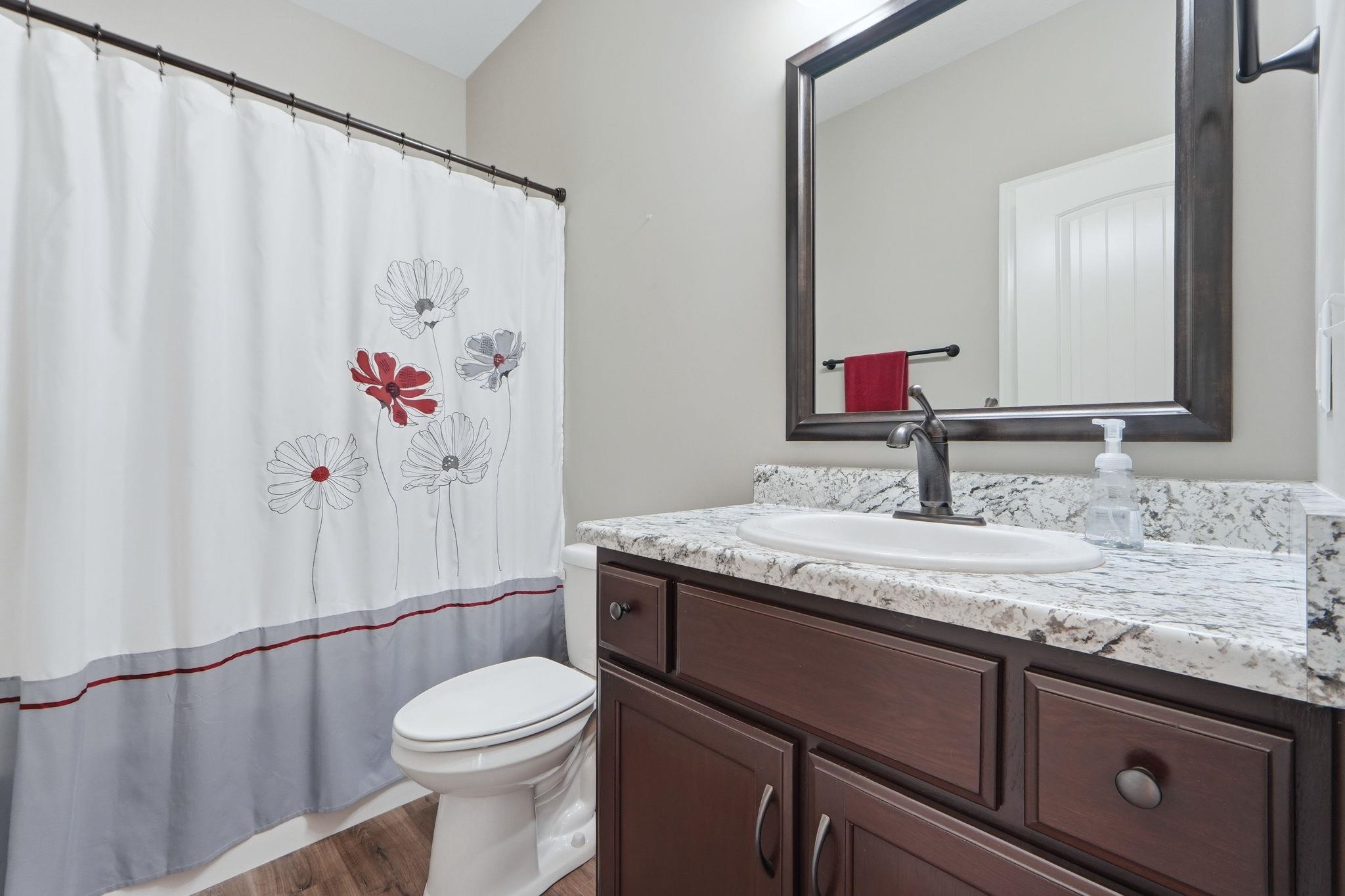 Full bath featuring vanity, a shower with shower curtain, and wood finished floors
